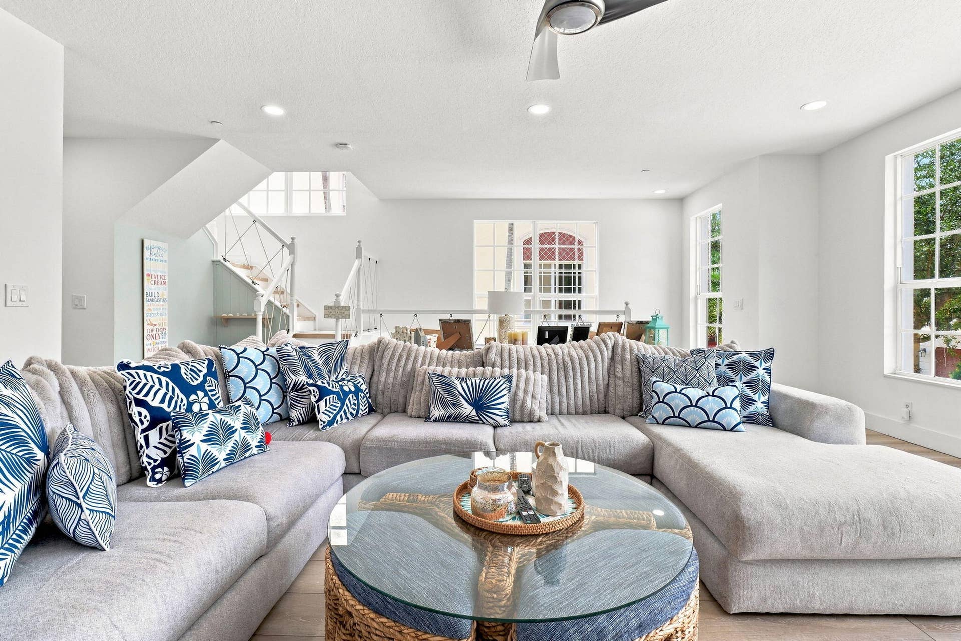 Spacious living area featuring high ceilings, recessed lighting, large windows and an open staircase
