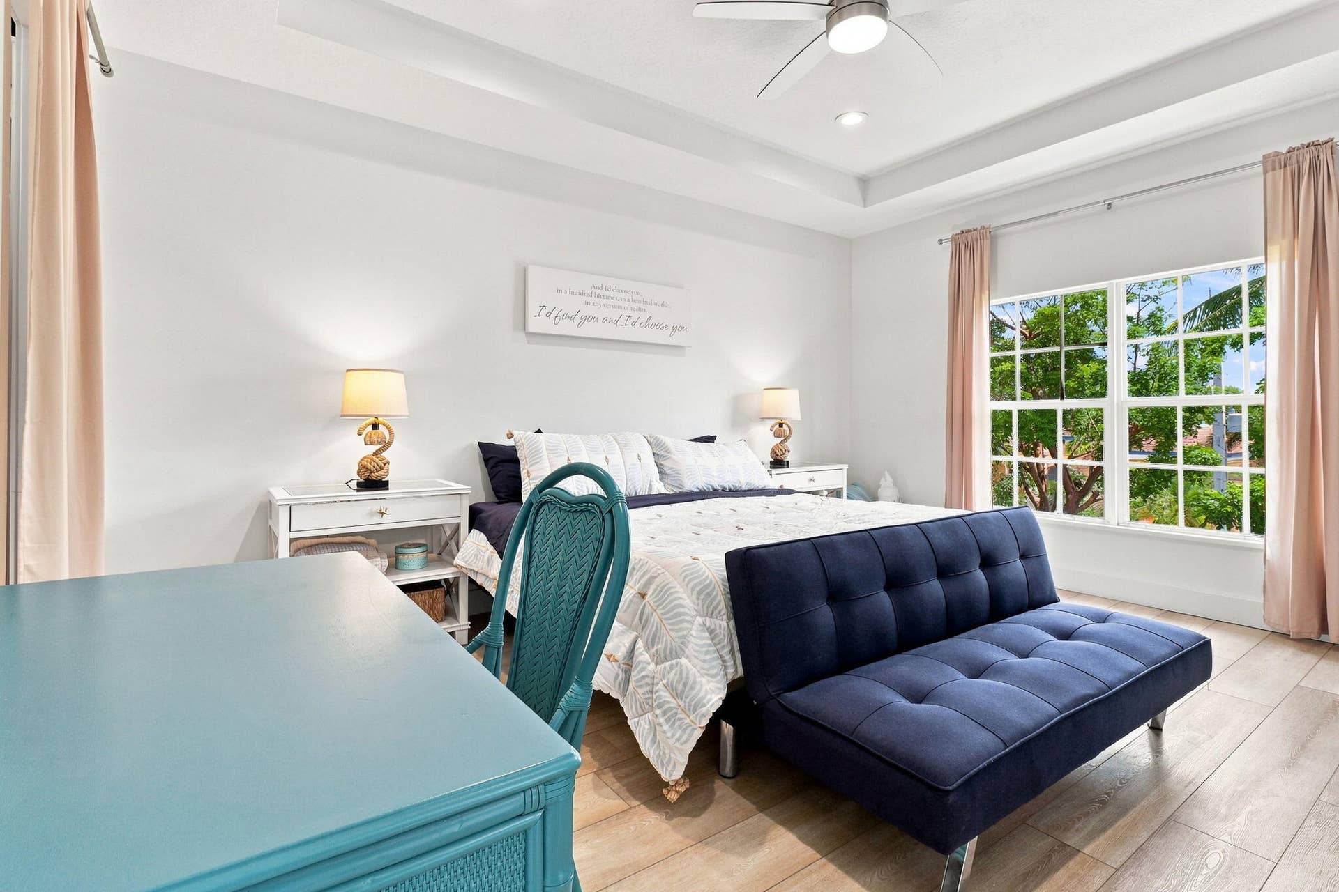 Tray ceiling with a ceiling fan, luxury vinyl flooring and a large window