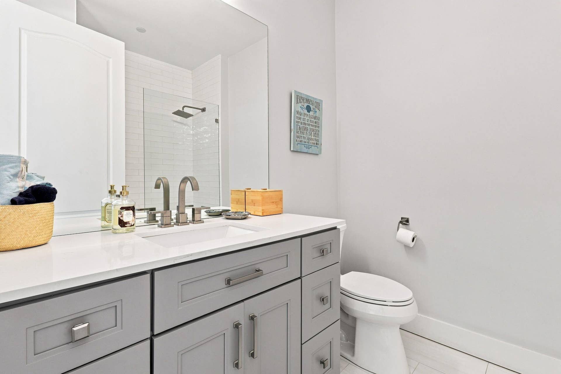 Vanity with light gray shaker cabinetry, white countertop and dual-handle brushed nickel faucet
