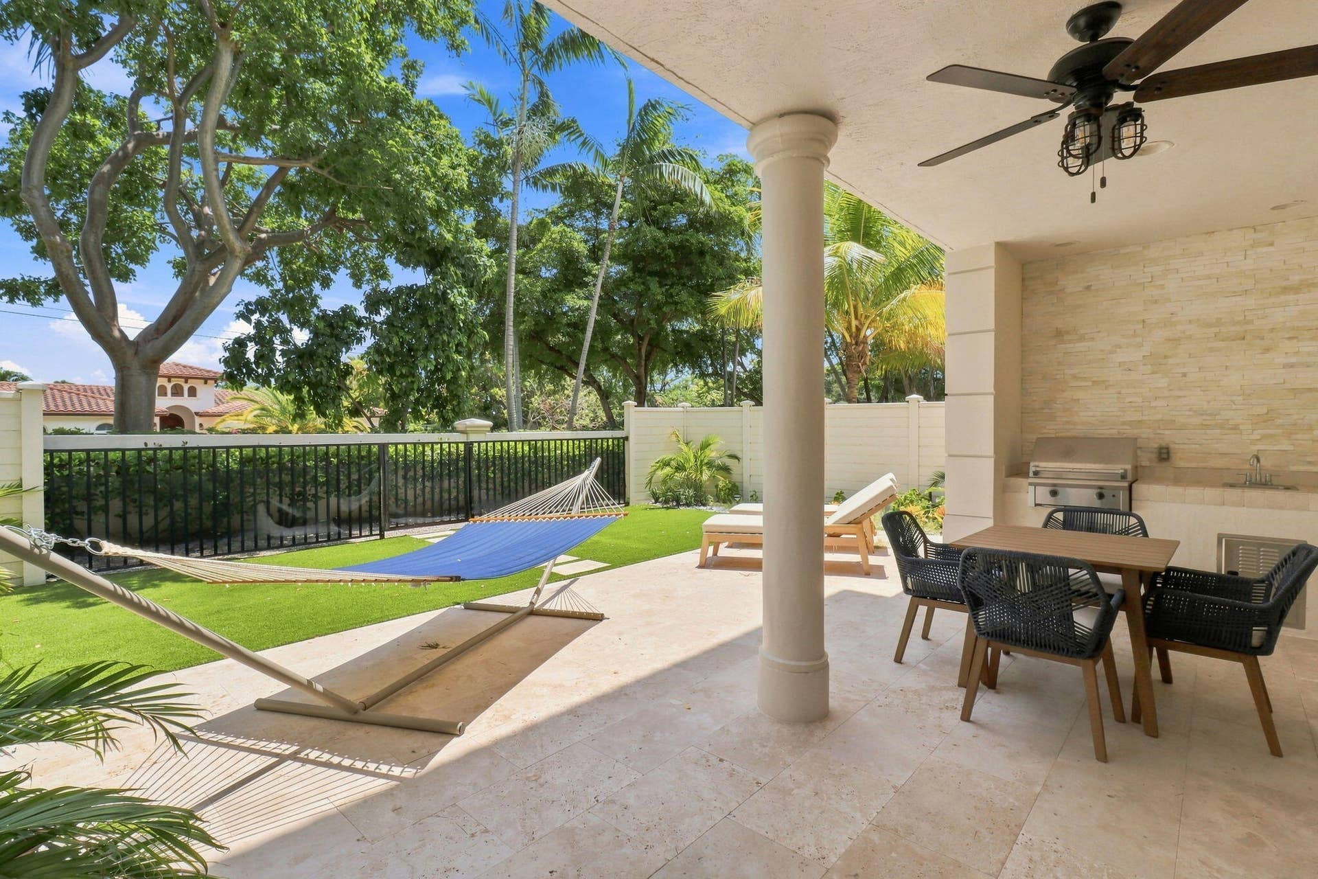 Lanai with integrated outdoor kitchen, ceiling fan with light fixture and stone-tiled accent wall