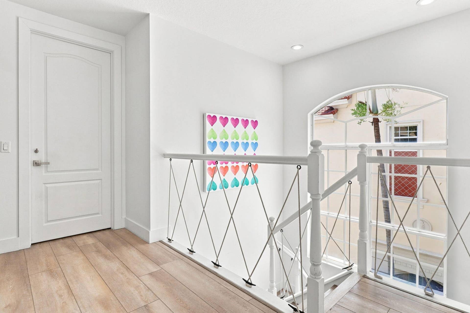 Bright walls, luxury vinyl flooring, white paneled door, recessed lighting and nautical railings