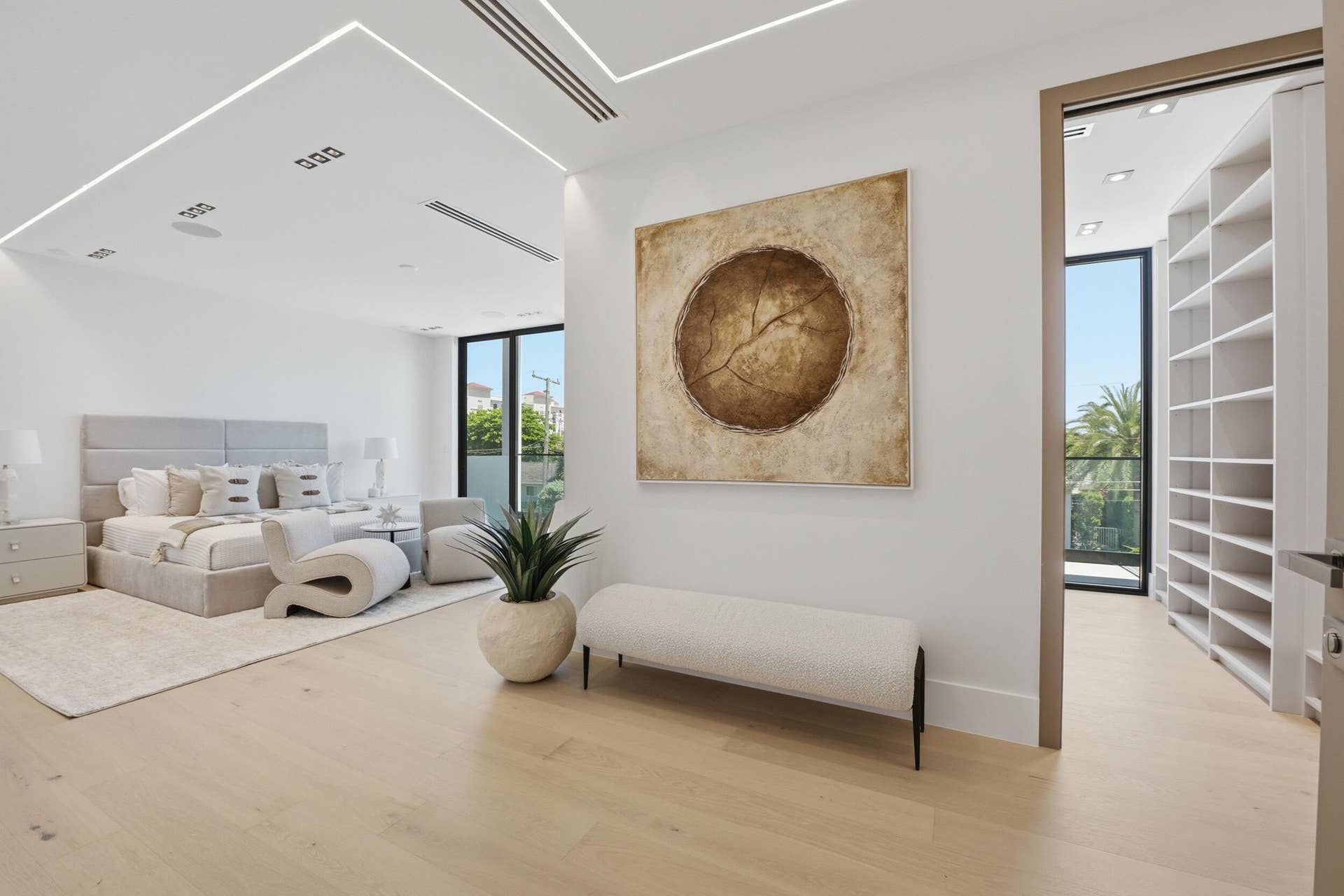 Light wood-finish flooring with recessed ceiling lighting, a built-in wall of shelving, full-height windows, and a patio door