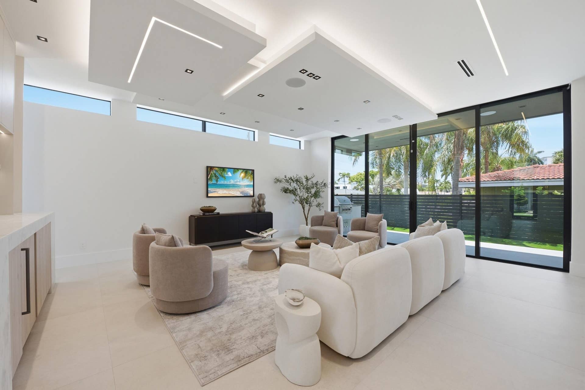 Spacious living area featuring large format tile flooring, recessed and linear ceiling lighting, transom windows, and full-height glass doors