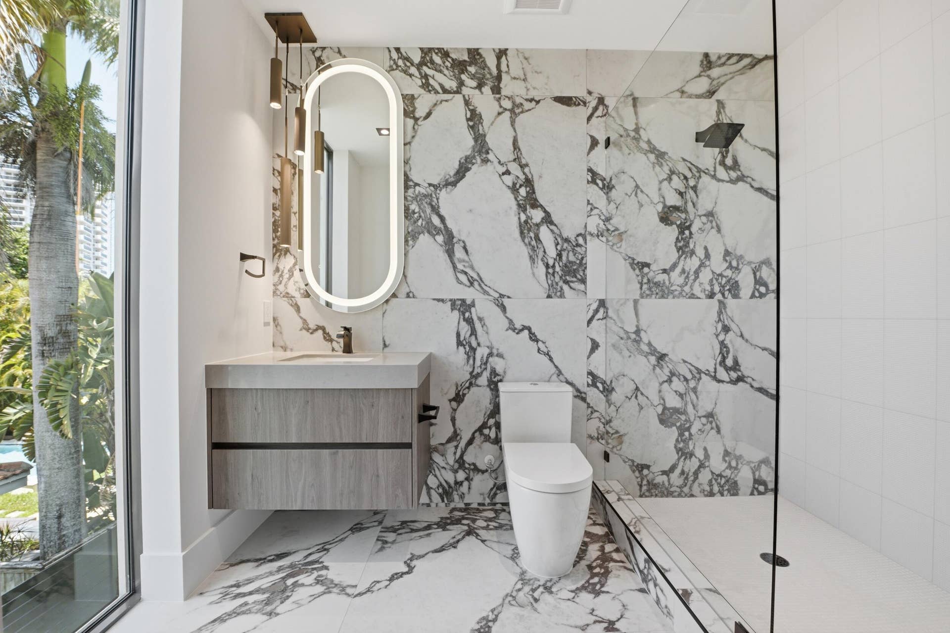 Floating vanity with wood-finish cabinetry, illuminated oval mirror, and a sleek rectangular sink