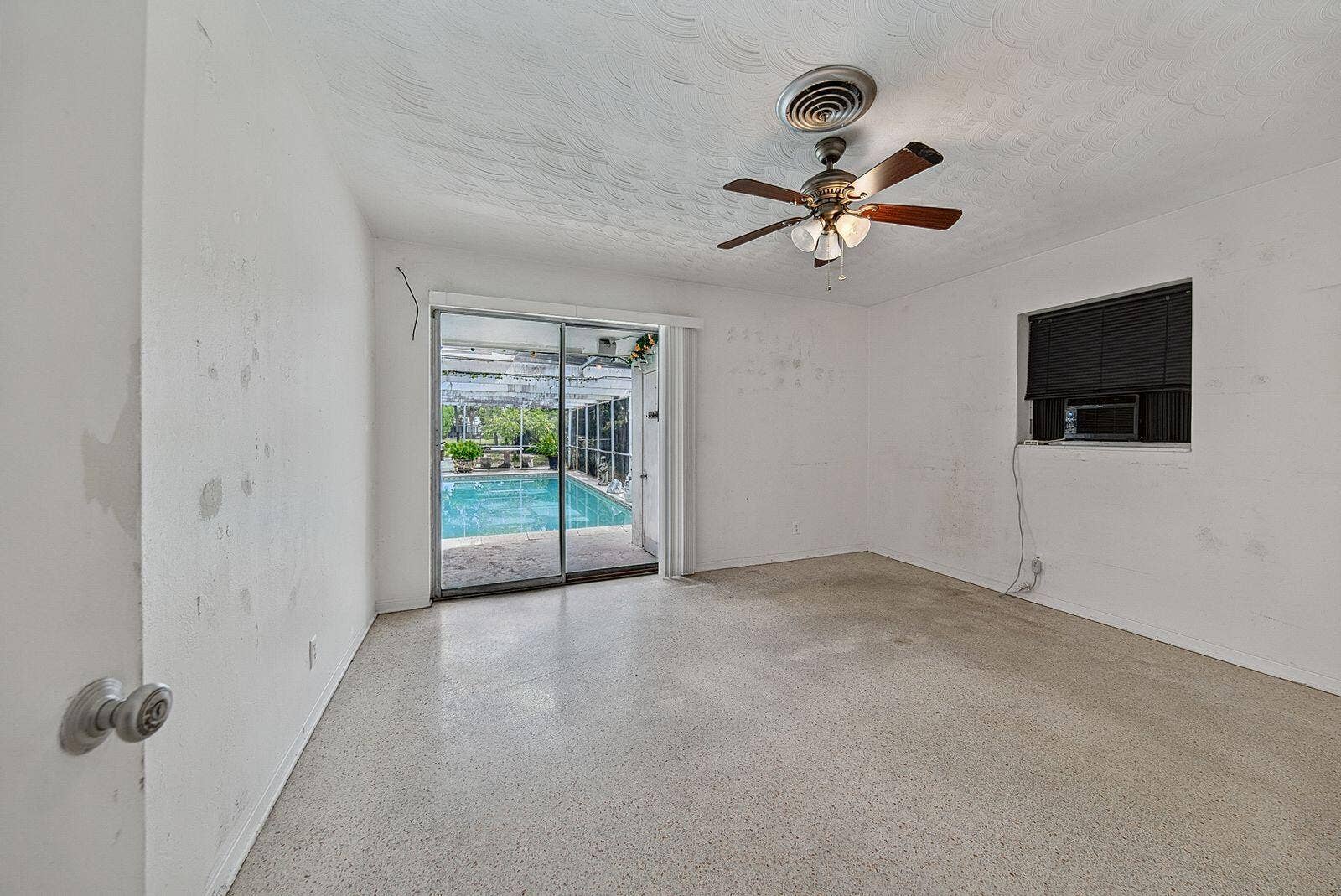 201 NE 29th Street, Wilton Manors, FL 33334 Spacious bedroom with terrazzo flooring and sliding-glass doors opening directly to the pool area.