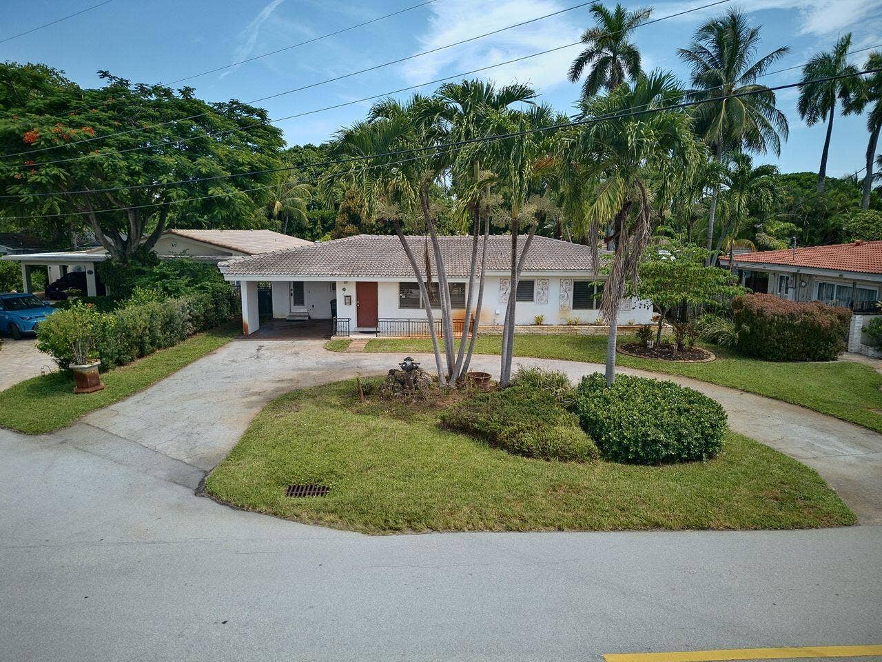 201 NE 29th Street, Wilton Manors, FL 33334 Single-story residence with a circular driveway, mature palms and convenient covered entry.