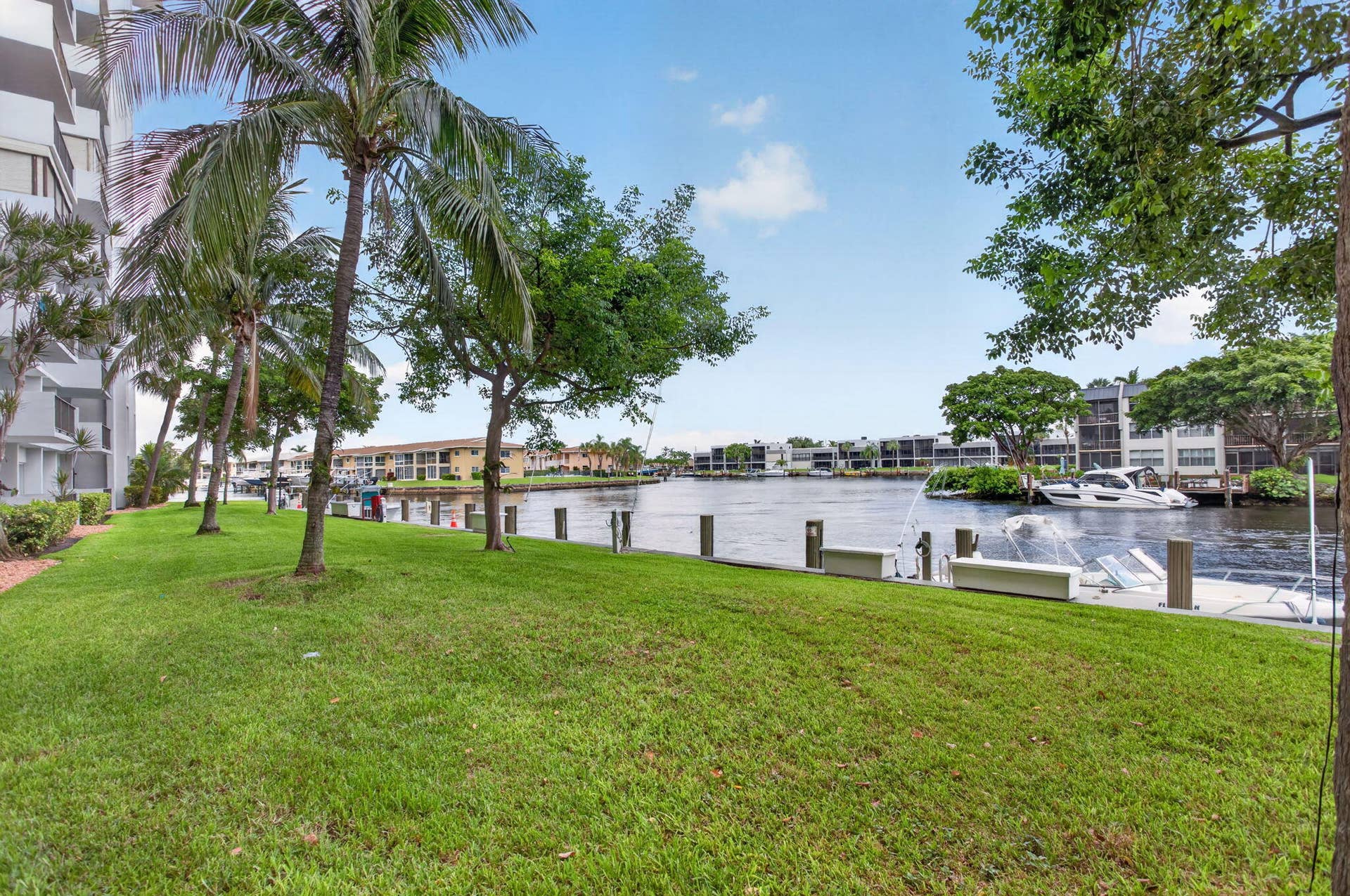 801 S Federal Highway, #1103, Pompano Beach, FL 33062 Grassy waterfront area with palm trees, mature trees, and a dock with water features