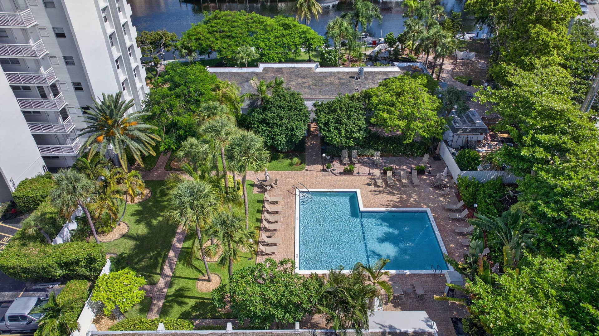 801 S Federal Highway, #1103, Pompano Beach, FL 33062 Expansive outdoor space featuring a rectangular swimming pool with a paved surround, lush landscaping, and mature palm trees