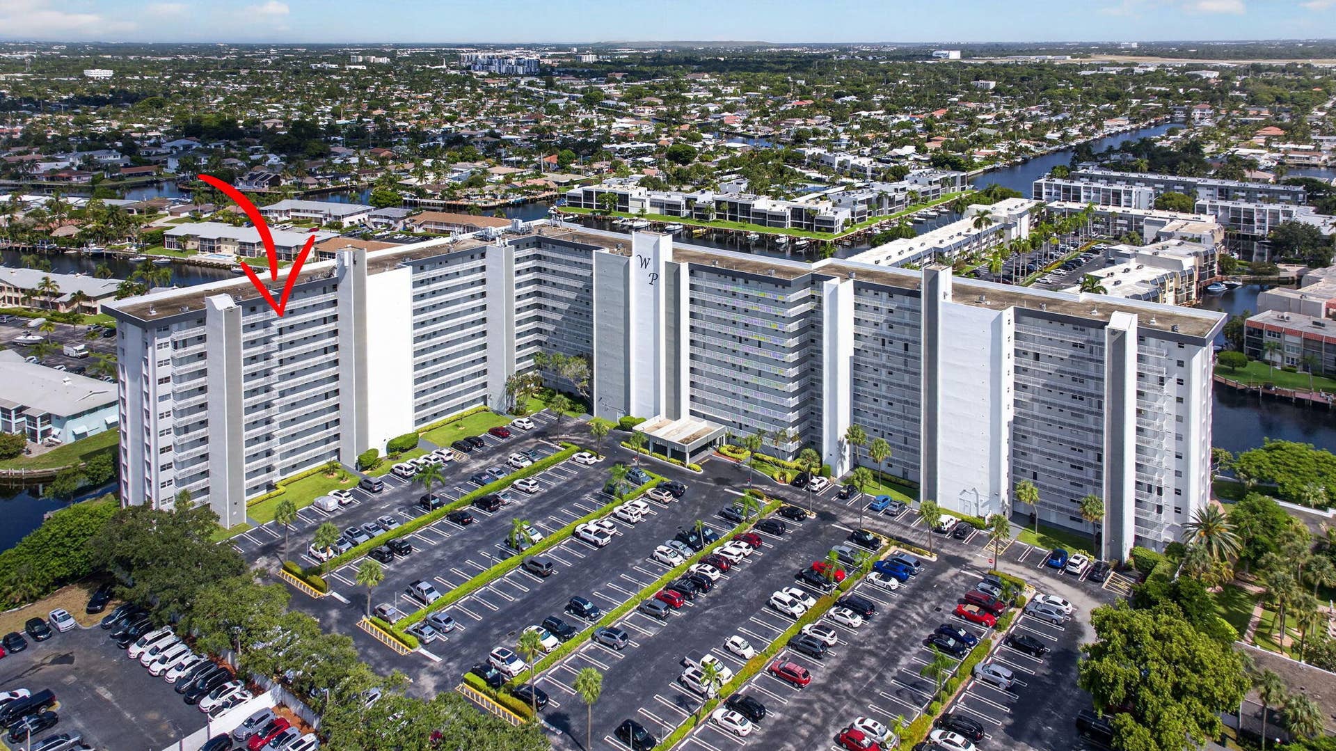 801 S Federal Highway, #1103, Pompano Beach, FL 33062 High-rise building with multiple balconies and a large parking area, surrounded by canals and residential properties