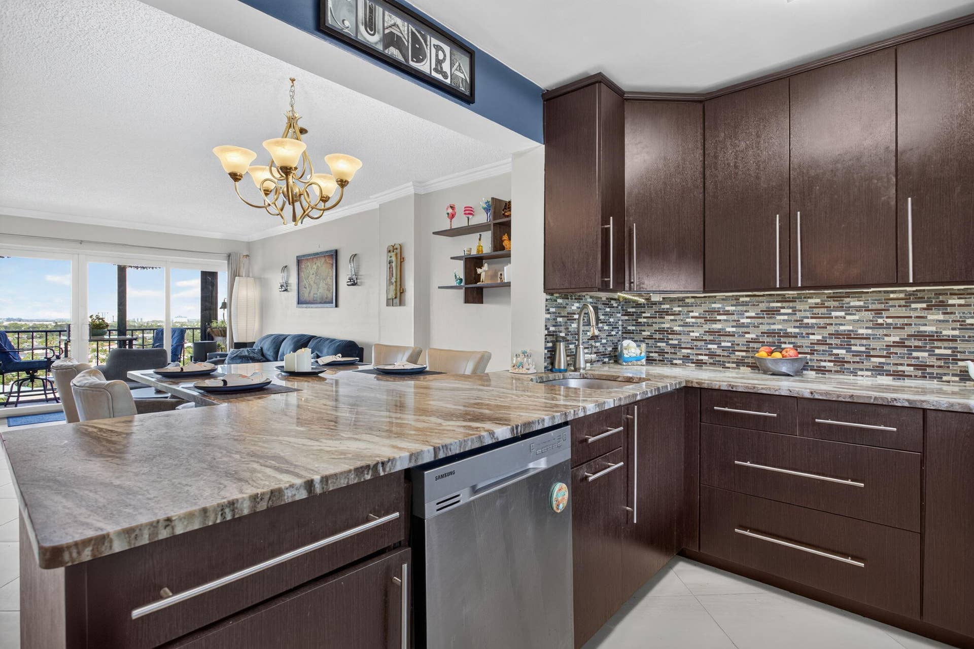801 S Federal Highway, #1103, Pompano Beach, FL 33062 Open-concept kitchen with dark wood-finish cabinetry, patterned stone countertops, and a mosaic tile backsplash