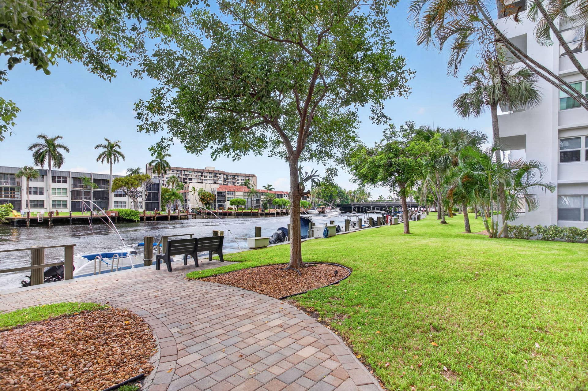 801 S Federal Highway, #1103, Pompano Beach, FL 33062 Waterfront property featuring a paver pathway, manicured lawn, and mature trees