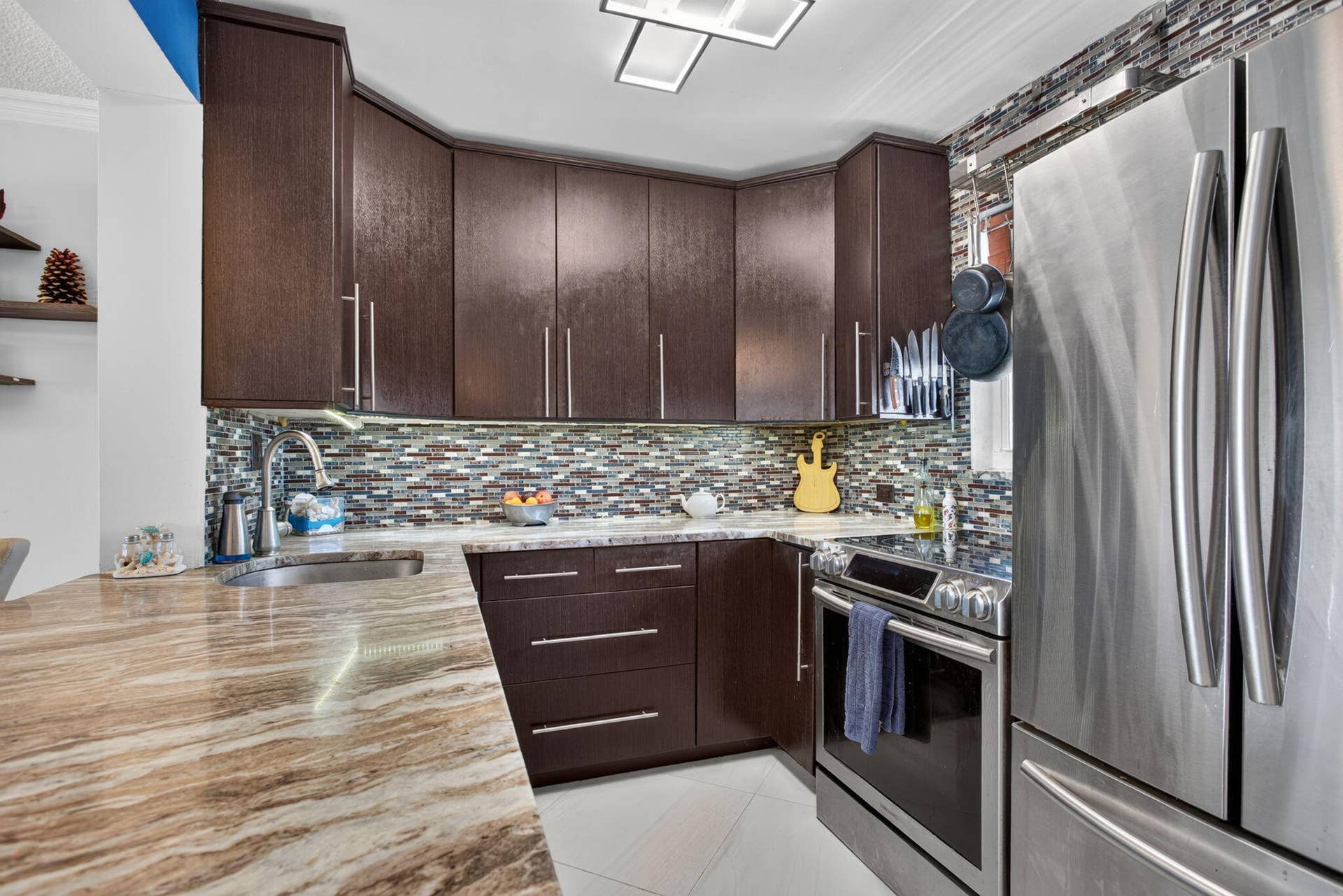 801 S Federal Highway, #1103, Pompano Beach, FL 33062 Rich wood-finish cabinetry, stainless steel appliances, mosaic tile backsplash, and a patterned countertop