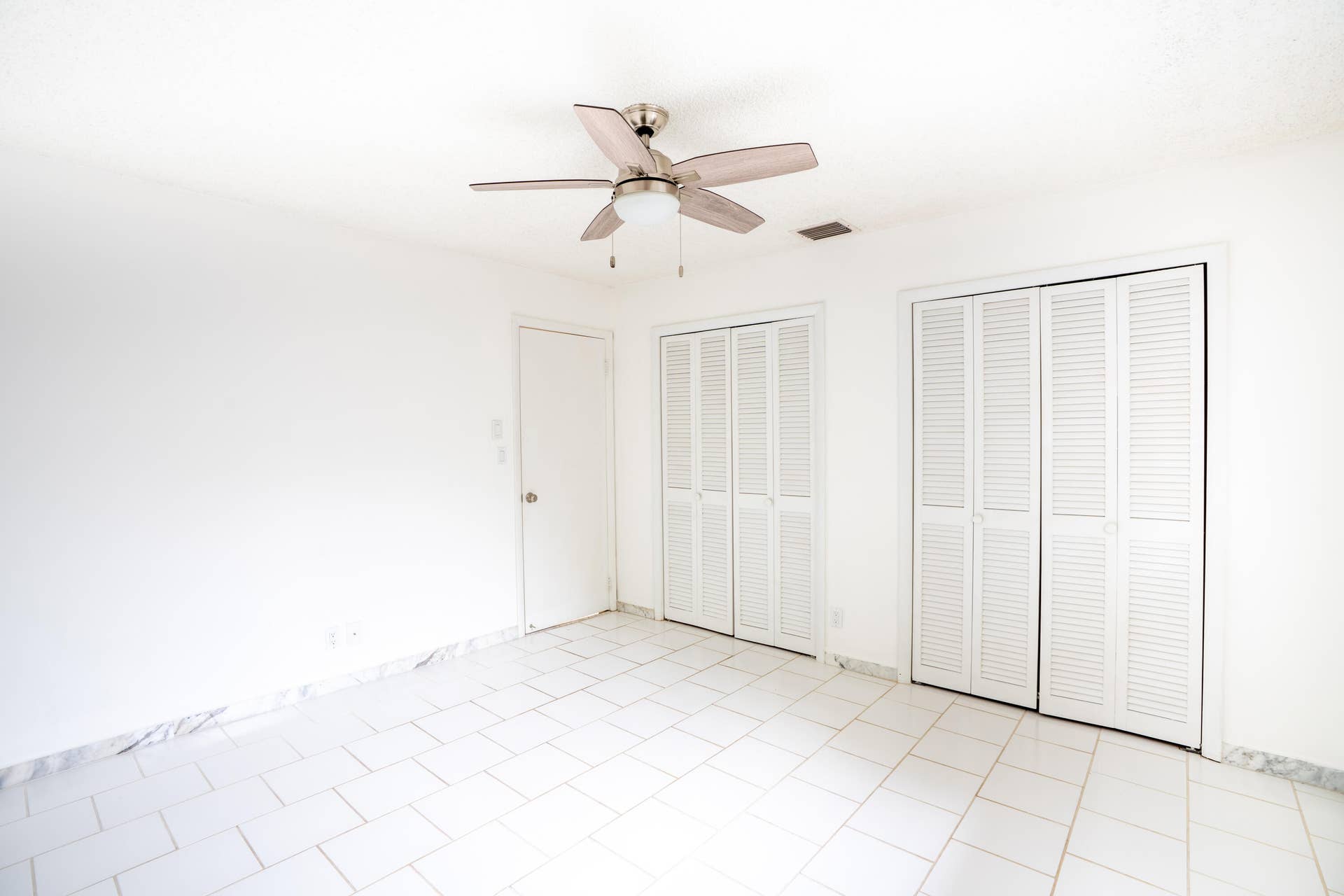 17 SE 8TH Terrace, Deerfield Beach, FL 33441 White tile flooring, clean white walls, two sets of louvered bifold closet doors, and a ceiling fan with integrated lighting
