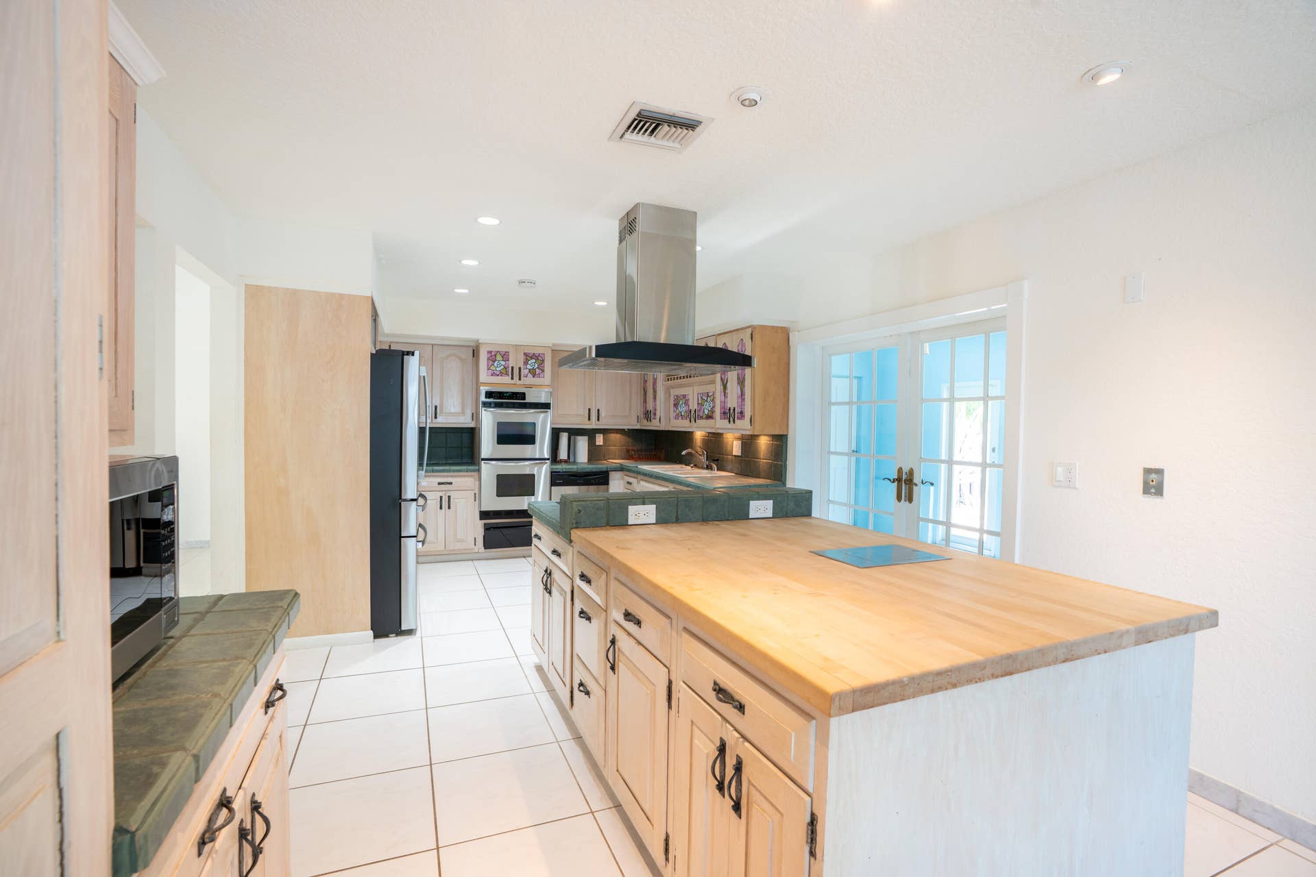 17 SE 8TH Terrace, Deerfield Beach, FL 33441 Expansive kitchen featuring a central island with a wood countertop, integrated cooktop, double wall ovens, and stainless steel range hood