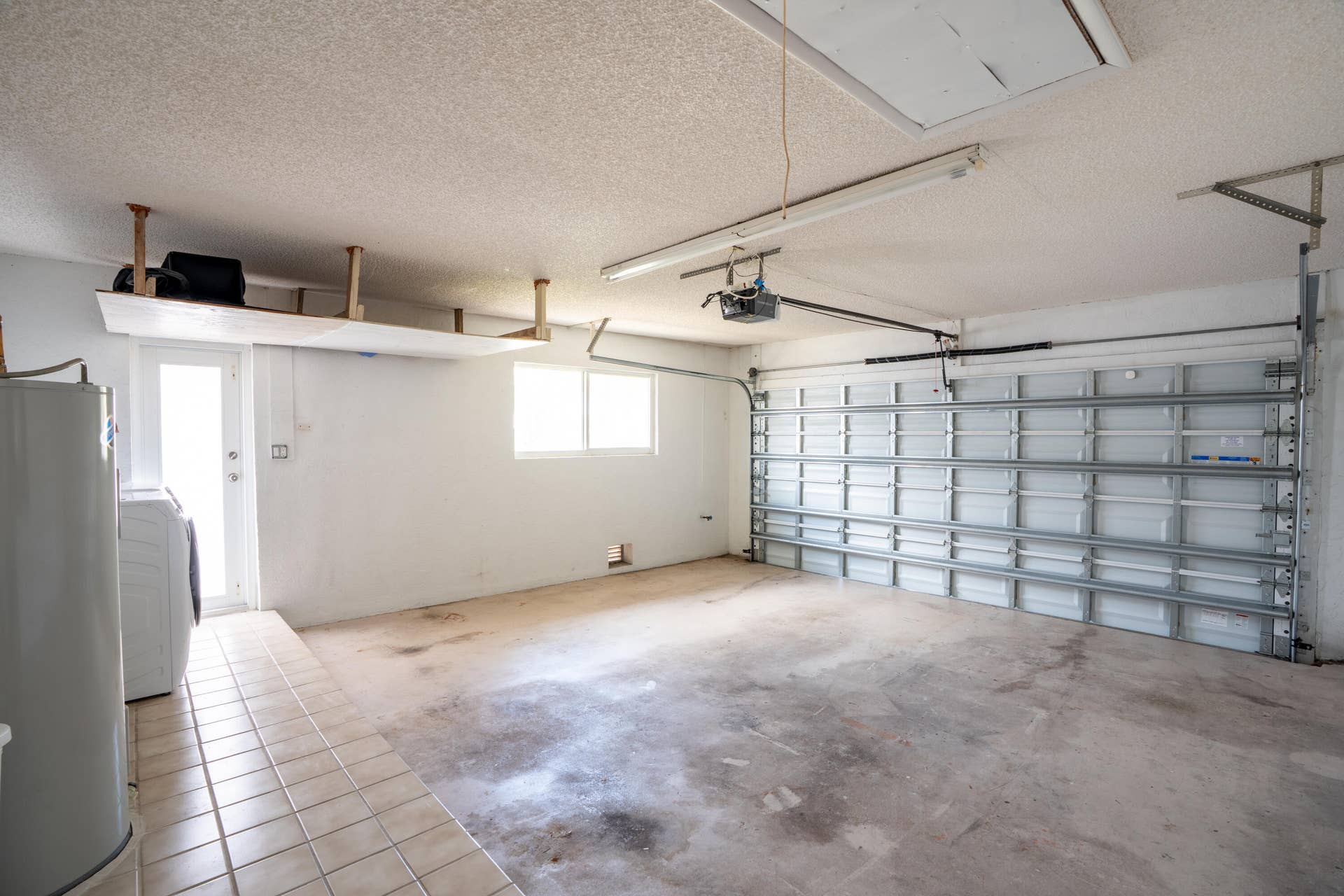 17 SE 8TH Terrace, Deerfield Beach, FL 33441 Garage with overhead storage, a garage door, tiled flooring, and a side access door