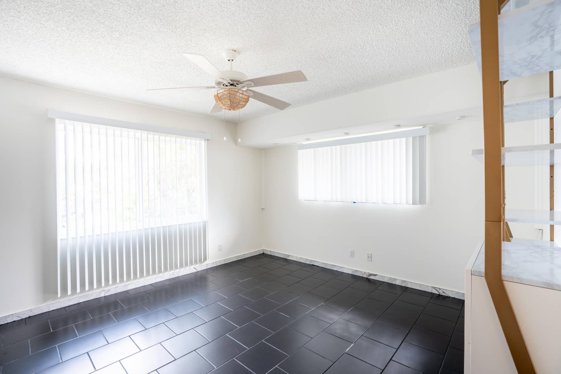 17 SE 8TH Terrace, Deerfield Beach, FL 33441 Dark tile flooring, white walls, ceiling fan, multiple windows with vertical blinds, and built-in shelving