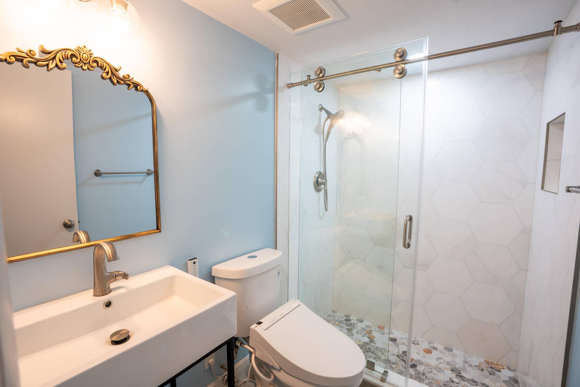 17 SE 8TH Terrace, Deerfield Beach, FL 33441 Floating vanity with a rectangular basin sink, brushed nickel faucet, and ornate gold-framed mirror