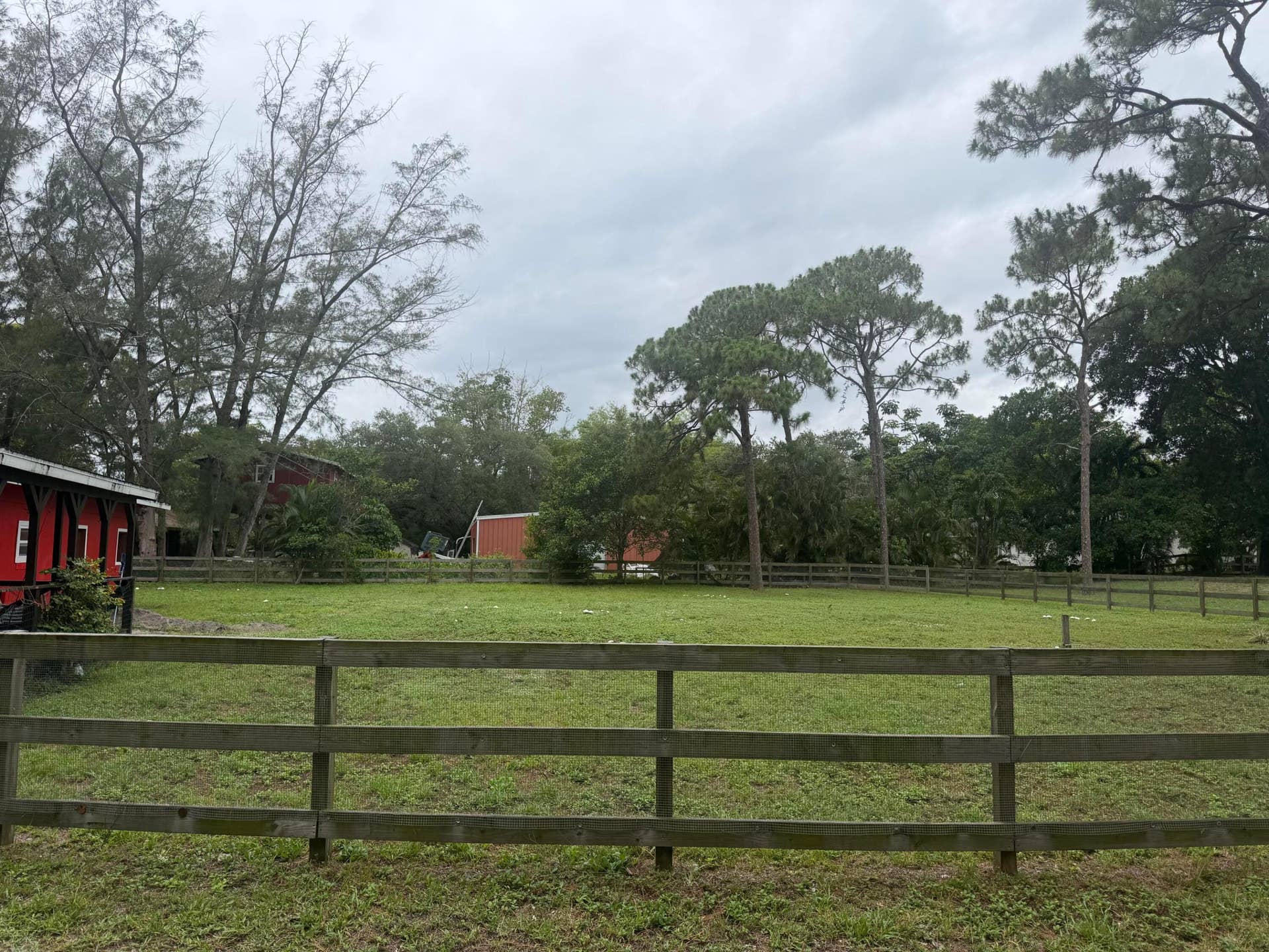 4020 Vinkemulder Road, Coconut Creek, FL 33073 Expansive green space featuring a wood fence, mature trees, and a red outbuilding