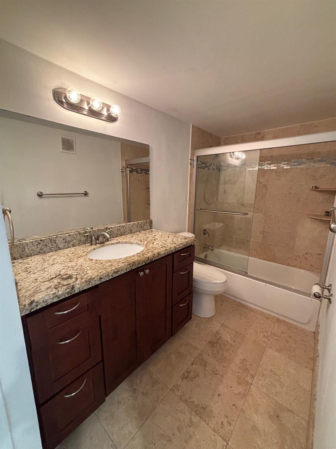 Dark wood-finish vanity with ample storage, a granite-finish countertop, and a single basin