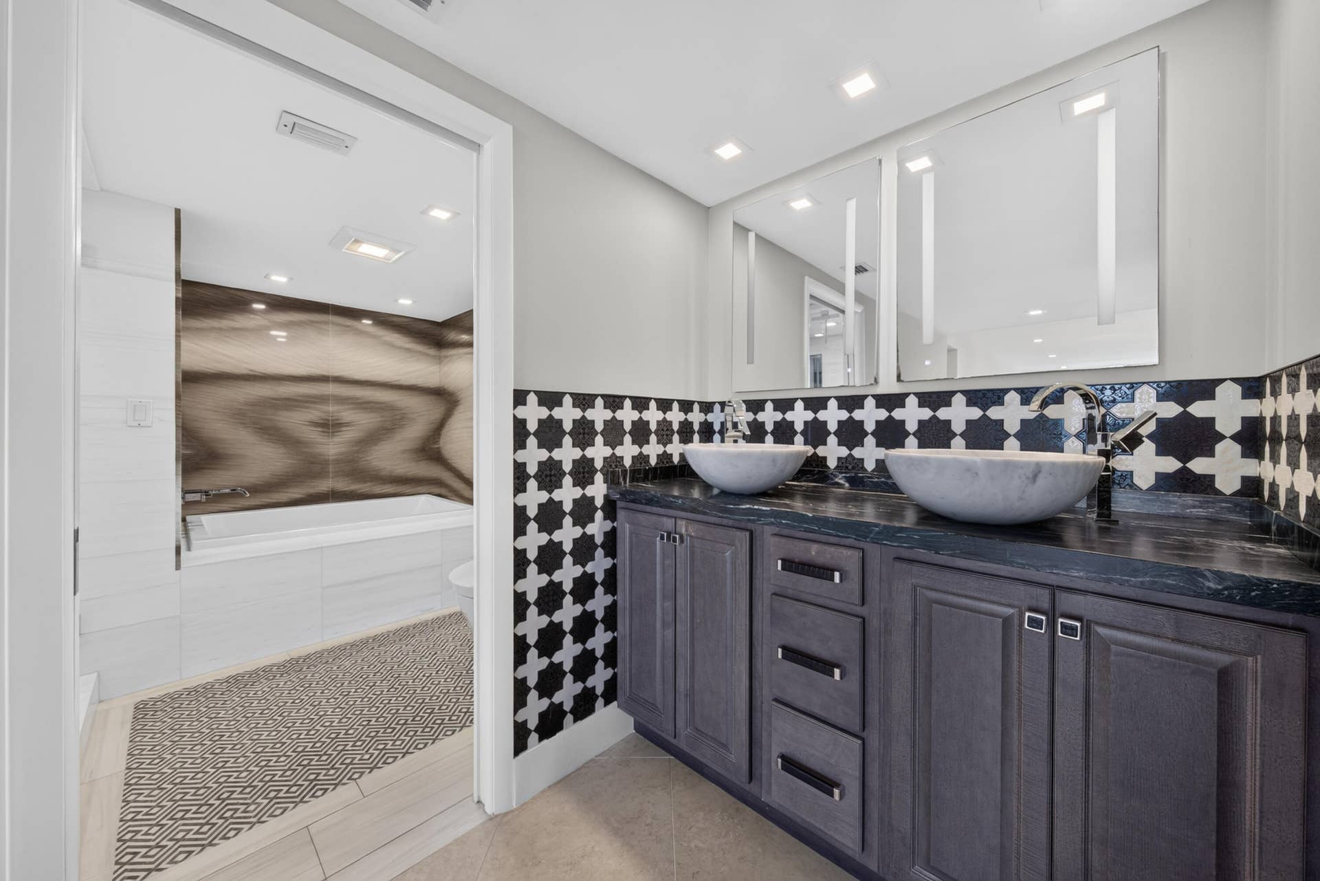 3900 Galt Ocean Drive, #2417, Fort Lauderdale, FL 33308 A custom dual vanity, vessel sinks, illuminated mirrors and bold tilework create a distinctive luxury retreat.