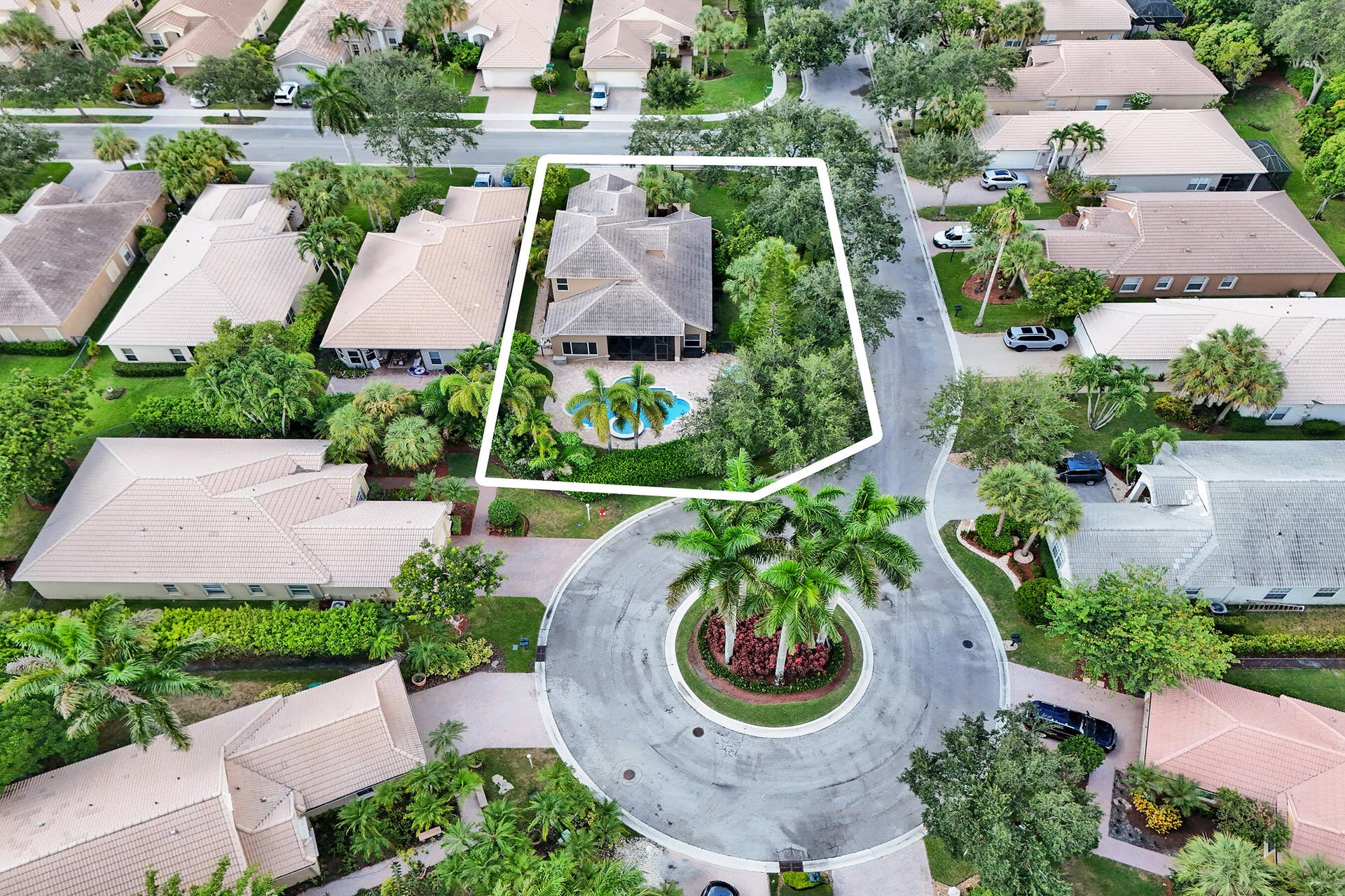 Residential property featuring a screened-in pool, lush landscaping, and a paver patio