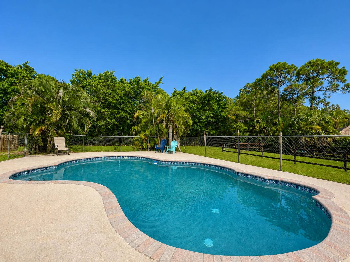 Crystal Clear Fenced In Pool Connected to Cover Patio, Outdoor Dining, Fire Pit Area and overlooking Barn 1, Paddocks and Flat Work Area