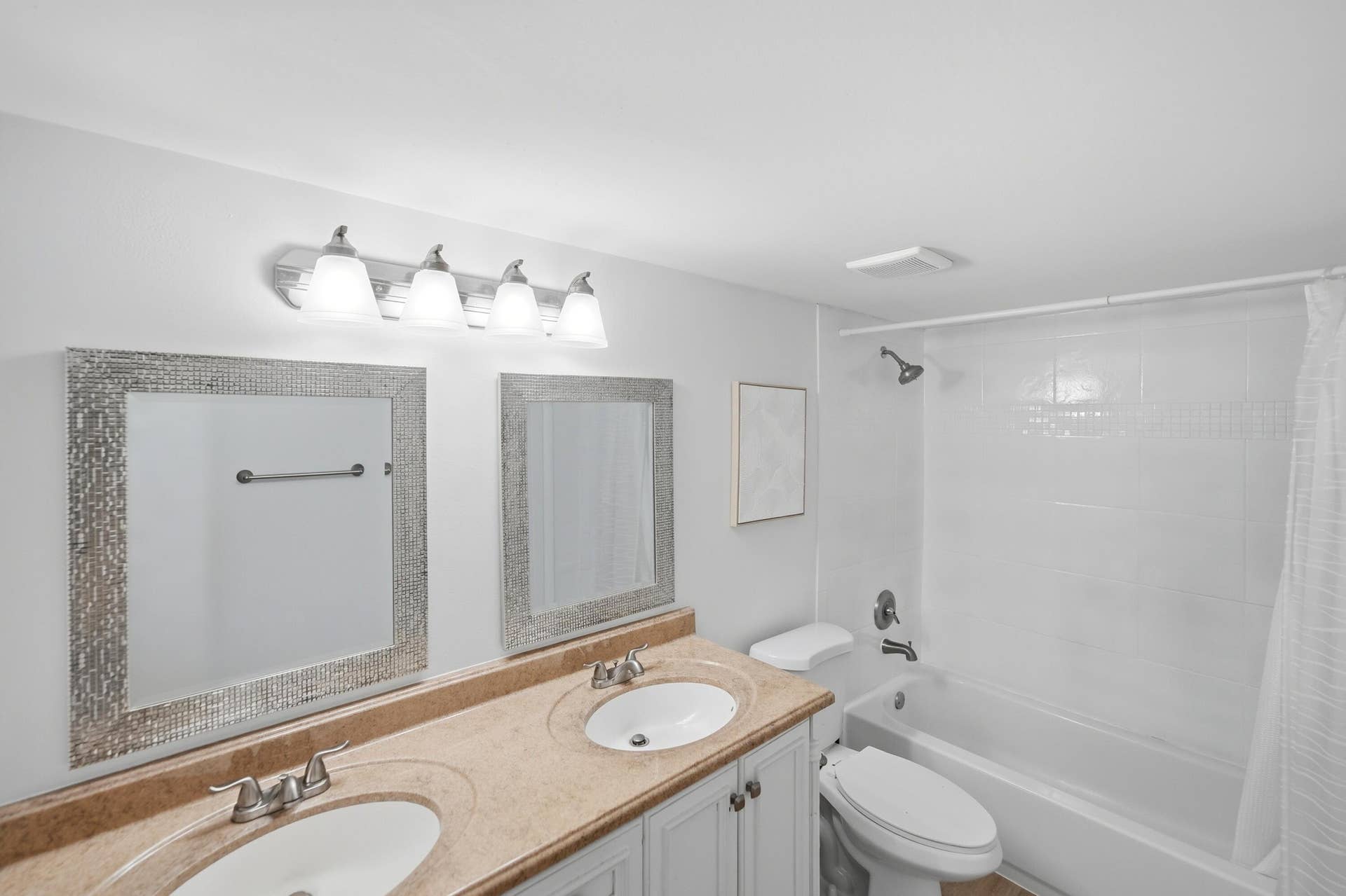 Dual vanity with two integrated sinks, textured framed mirrors, and a four-light fixture