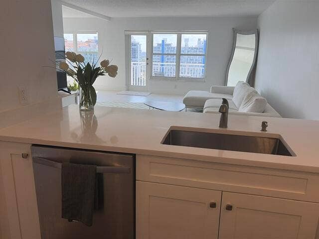 Kitchen island with a stainless steel undermount sink, brushed nickel faucet, and integrated stainless steel dishwasher