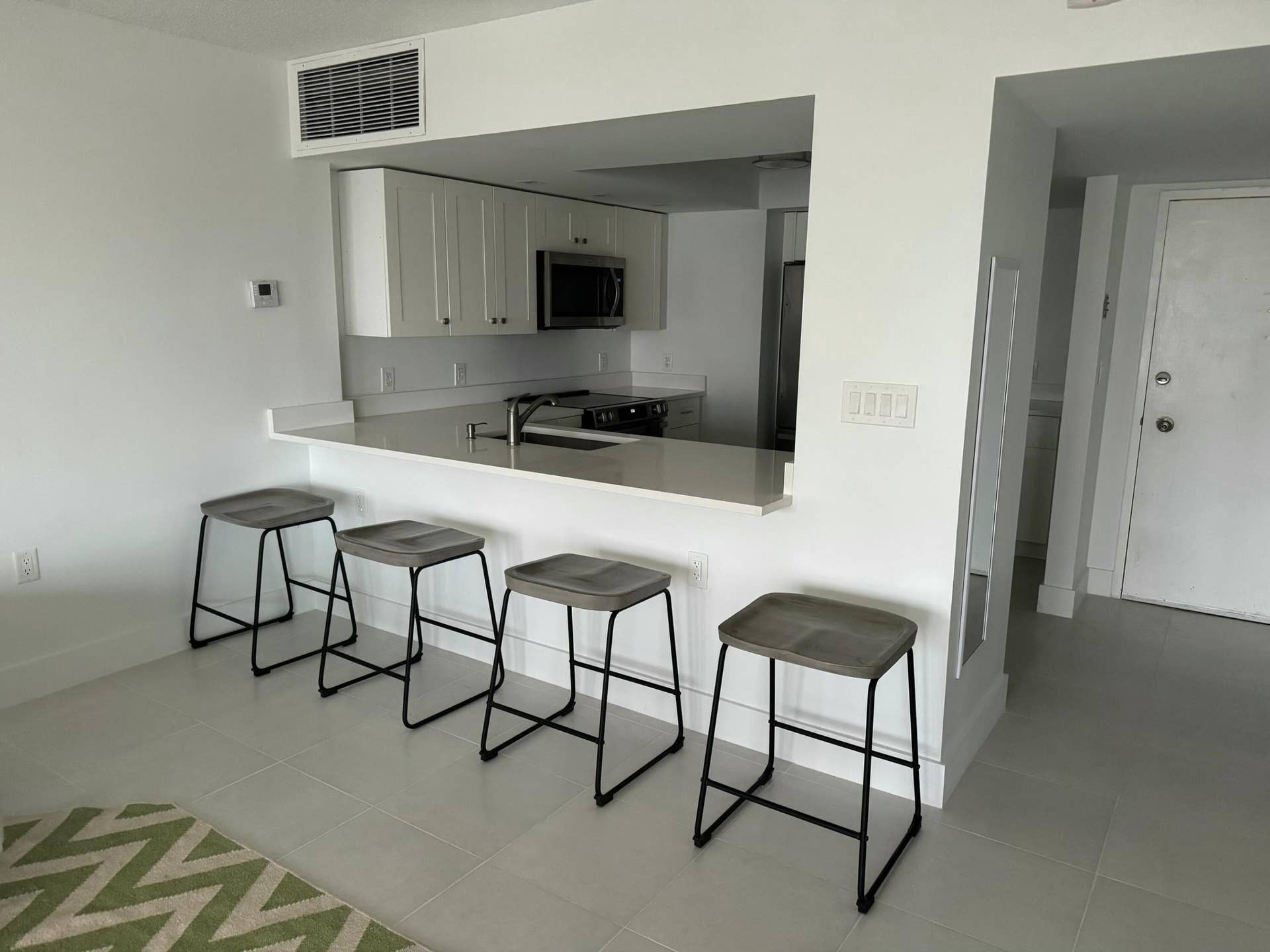 Open-concept kitchen with white shaker cabinetry, stainless steel appliances, and a pass-through bar with seating