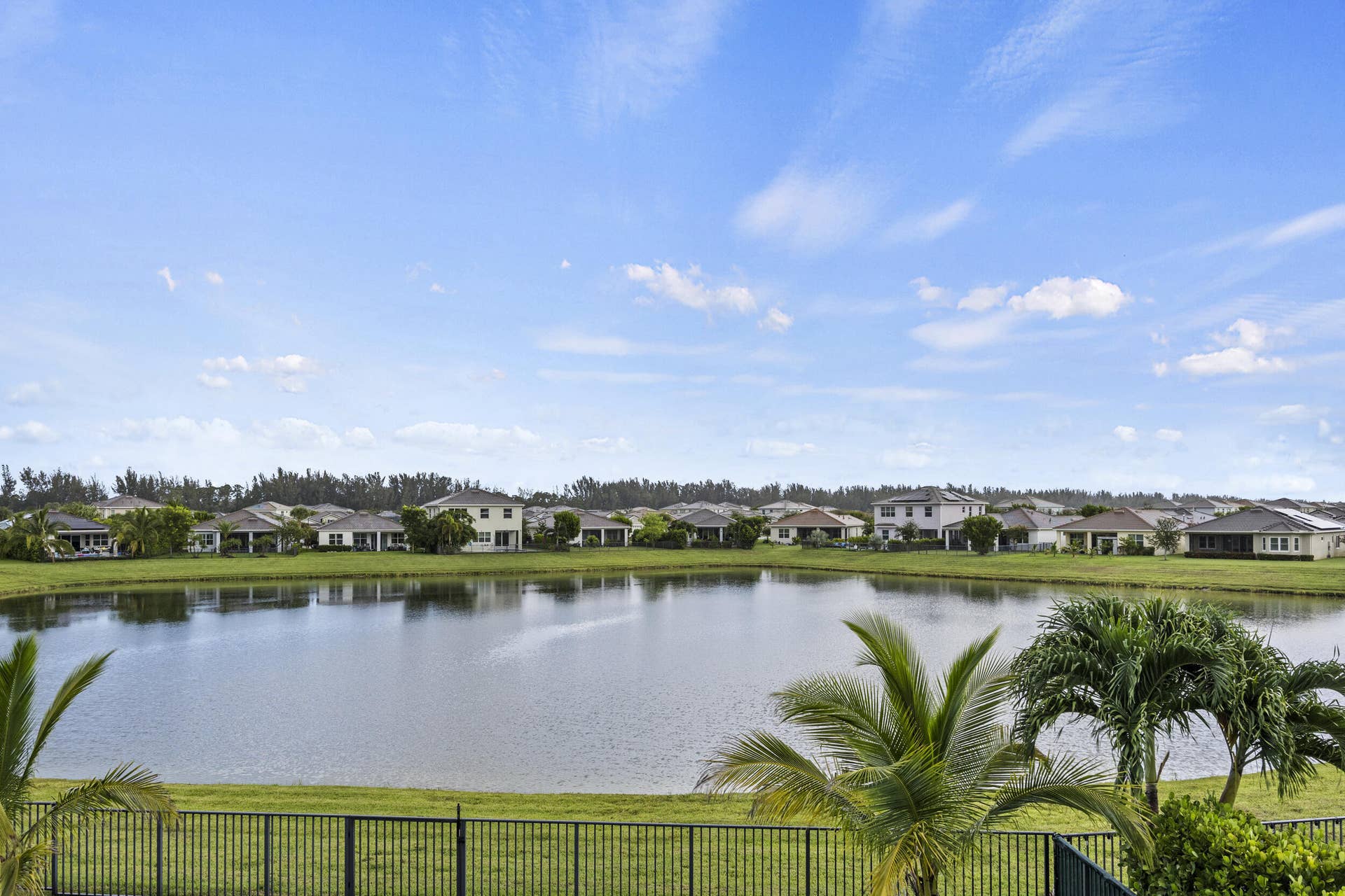 16007 Whippoorwill Circle, Westlake, Westlake, FL 33470 Waterfront property featuring a black metal fence, green lawn, and mature palm trees