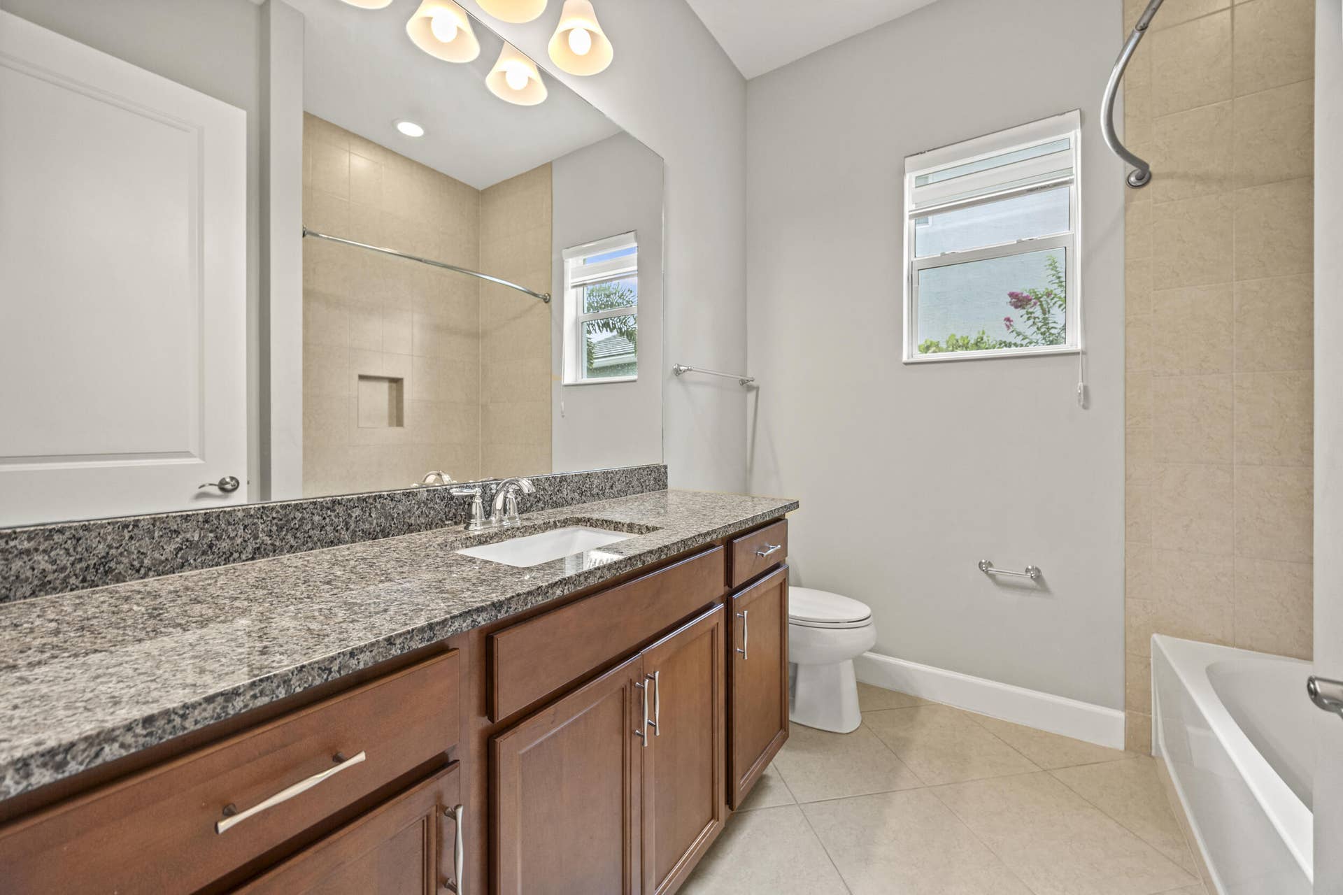 16007 Whippoorwill Circle, Westlake, Westlake, FL 33470 Dual-sink vanity with a stone countertop, wood-finish cabinetry, and tiled flooring