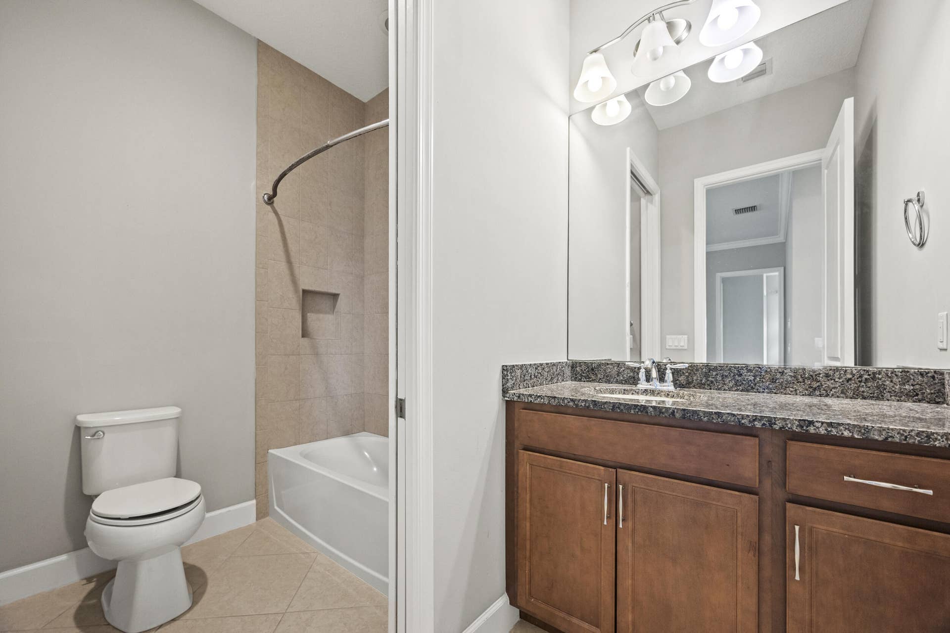 16007 Whippoorwill Circle, Westlake, Westlake, FL 33470 Bathroom featuring a tiled shower surround with built-in niche, a white tub, a vanity with a dark speckled countertop, wood-finish cabinetry, and a chrome faucet