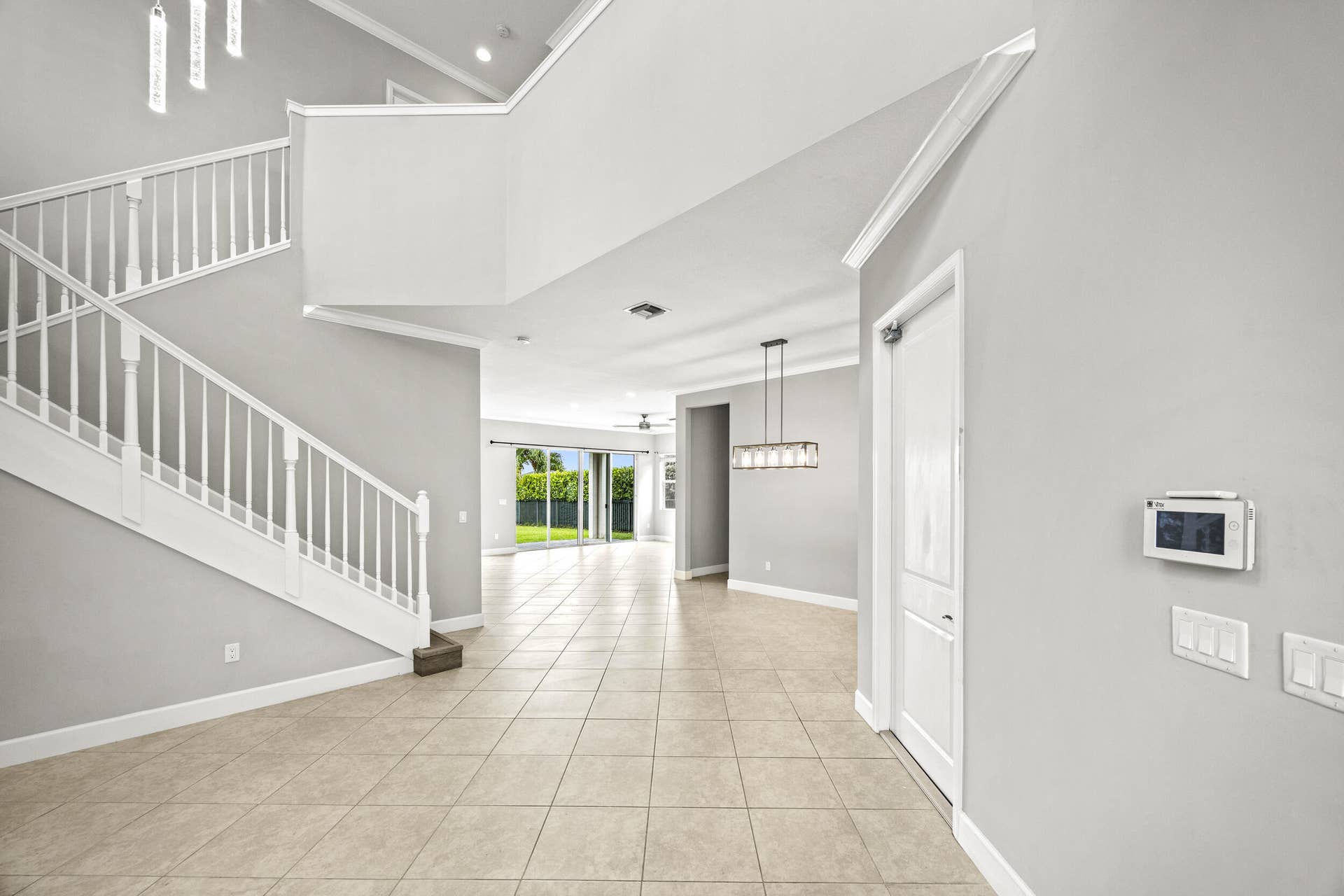 16007 Whippoorwill Circle, Westlake, Westlake, FL 33470 Two-story foyer with a grand staircase, tile flooring, crown molding, and a modern chandelier