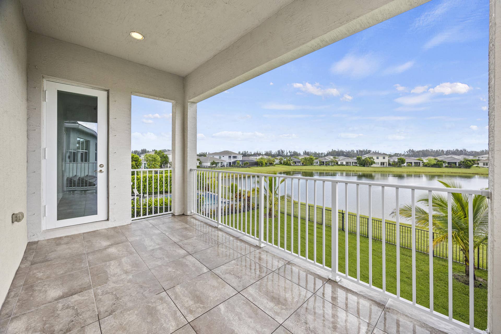 16007 Whippoorwill Circle, Westlake, Westlake, FL 33470 Spacious balcony with tiled flooring, white metal railing, and expansive water frontage