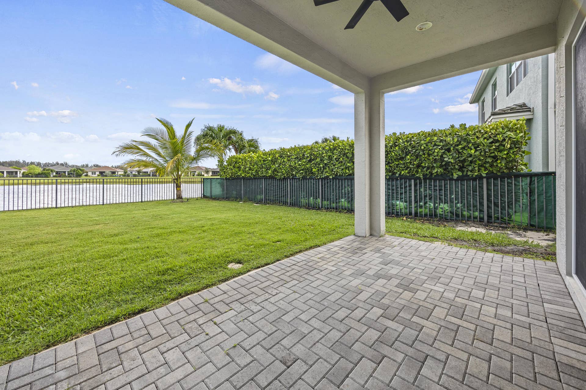 16007 Whippoorwill Circle, Westlake, Westlake, FL 33470 Expansive paver patio with covered overhead, leading to a manicured lawn and water frontage