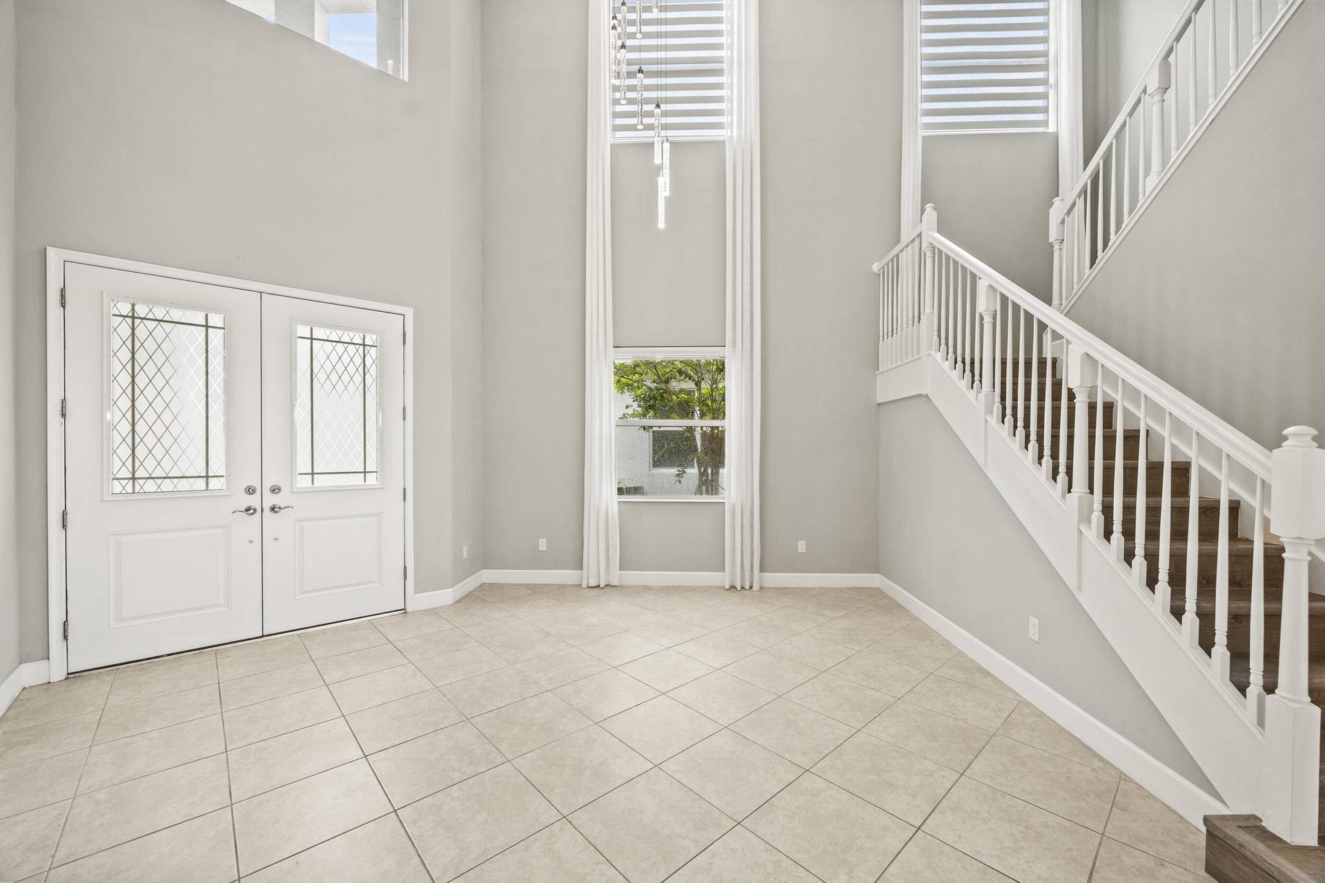 16007 Whippoorwill Circle, Westlake, Westlake, FL 33470 Two-story entry with double doors featuring decorative glass inserts, ceramic tile flooring, and a grand staircase with white railings