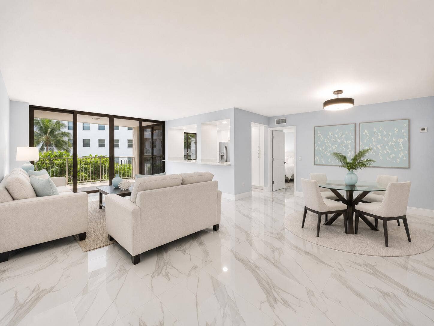 Polished light tile flooring throughout, bright recessed lighting, and a full-height impact glass sliding door opening to a private balcony. some furniture is virtually staged