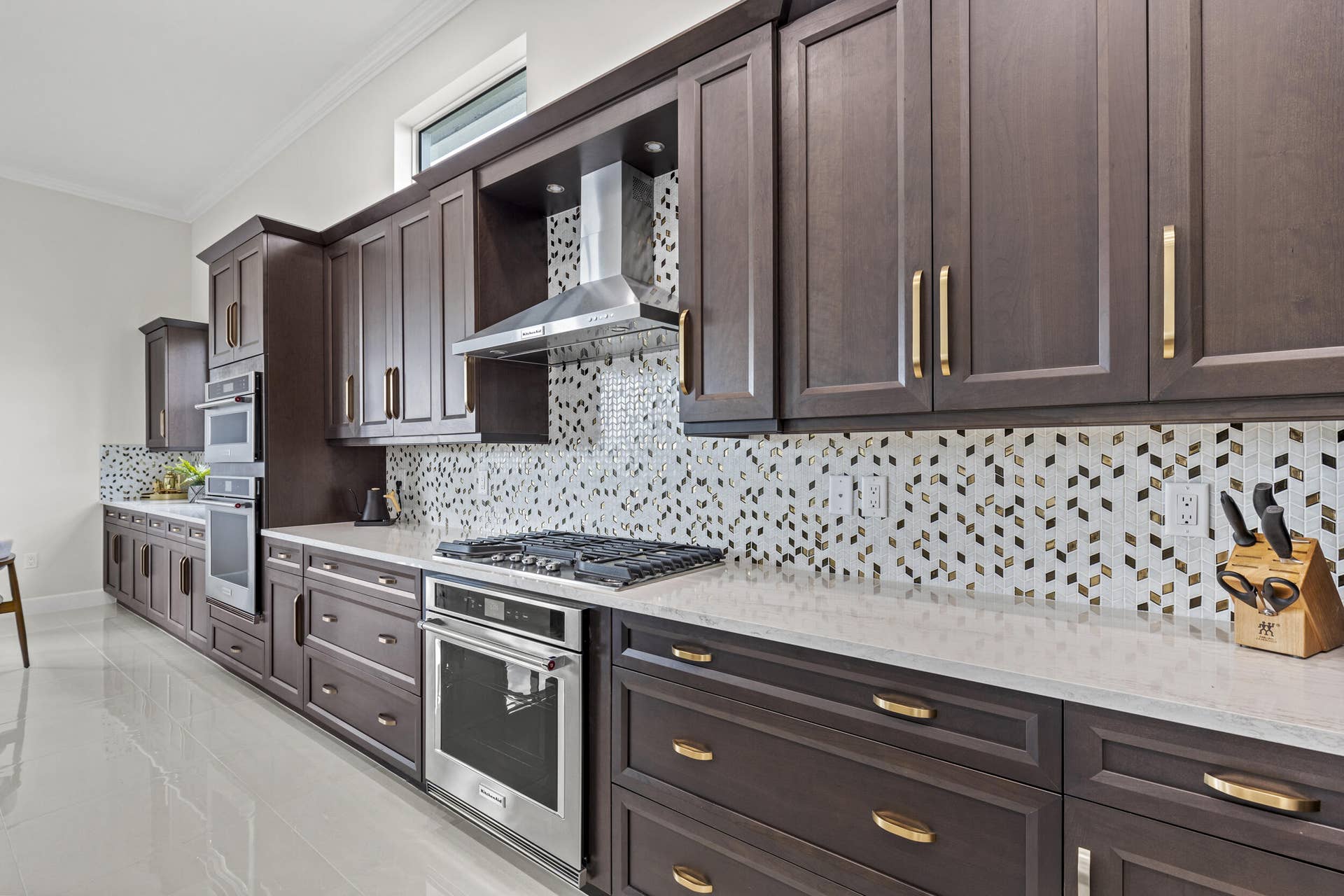14976 Woodlot Court, Westlake, FL 33470 Extensive dark wood-finish cabinetry with gold-tone hardware, light countertops, and a full tile backsplash