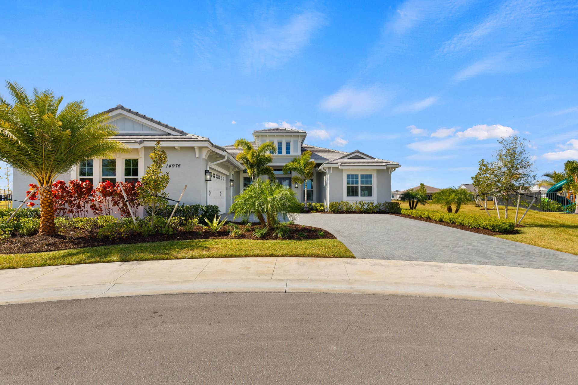 14976 Woodlot Court, Westlake, FL 33470 Modern exterior with a light gray facade, decorative shutters, a paved driveway, and mature landscaping