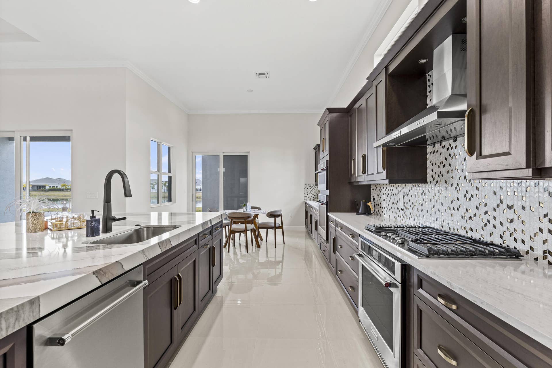 14976 Woodlot Court, Westlake, FL 33470 Expansive kitchen featuring a large central island, stainless steel appliances, custom cabinetry, tiled flooring, and a decorative backsplash