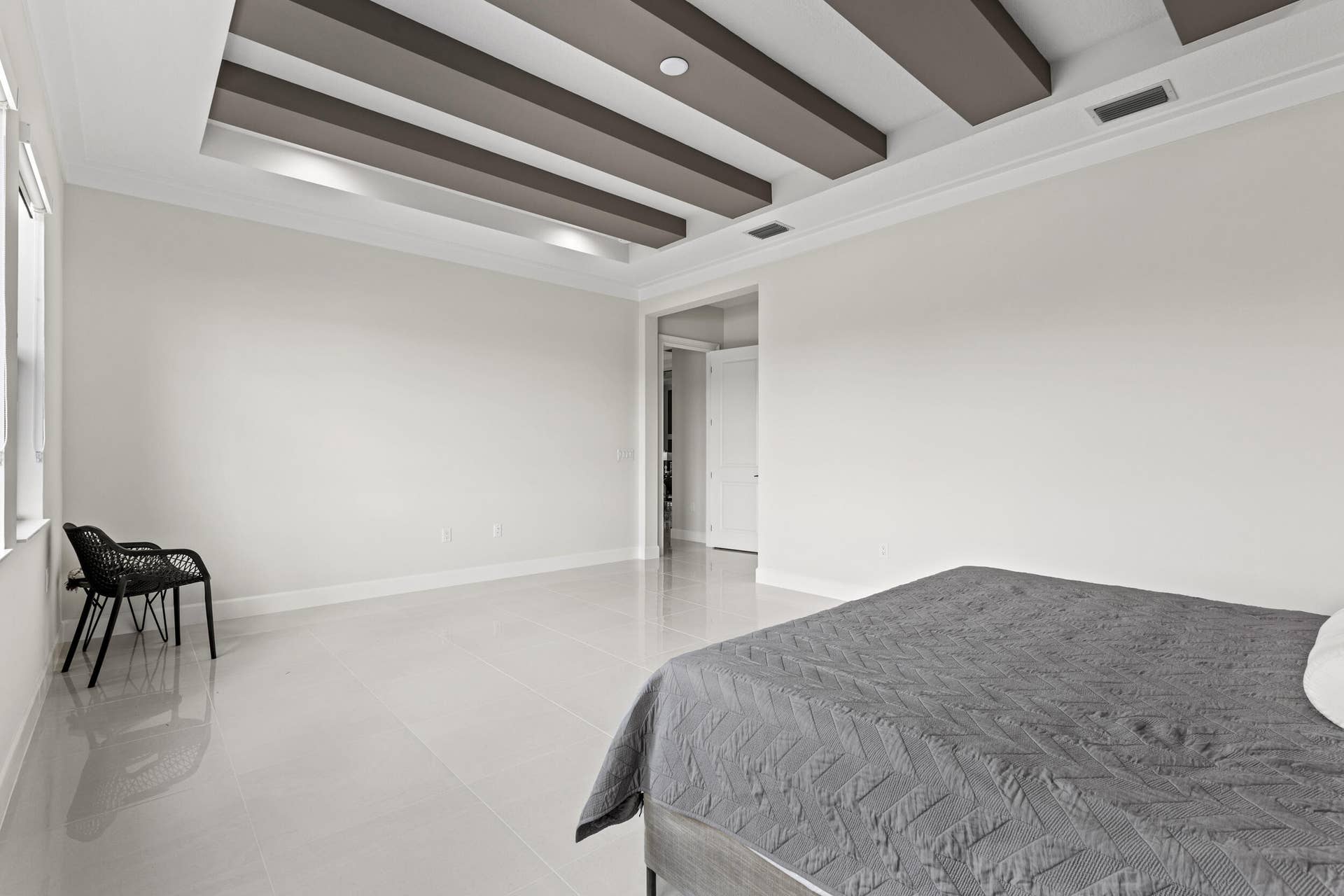 14976 Woodlot Court, Westlake, FL 33470 Owner's Suite featuring tray ceiling with recessed lighting and decorative beams, large window, light-toned flooring, and crown molding