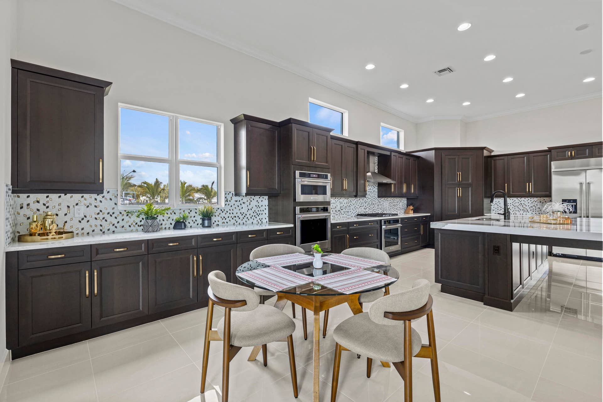 14976 Woodlot Court, Westlake, FL 33470 Expansive kitchen featuring dark wood-finish cabinetry, white countertops, a mosaic tile backsplash, and an oversized kitchen island