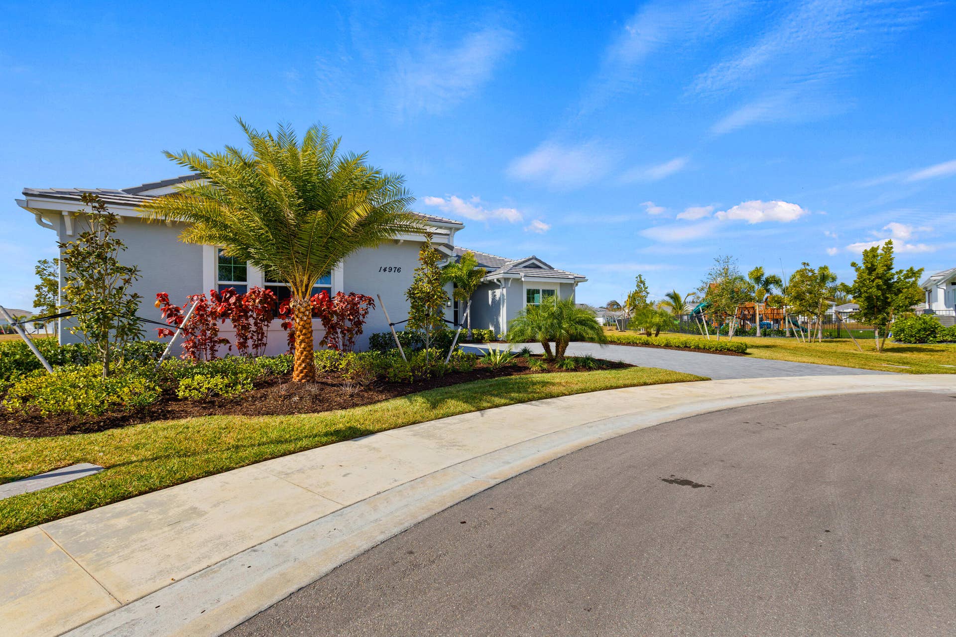 14976 Woodlot Court, Westlake, FL 33470 Single-story residence featuring a gray exterior, a tiled roof, and a paved driveway