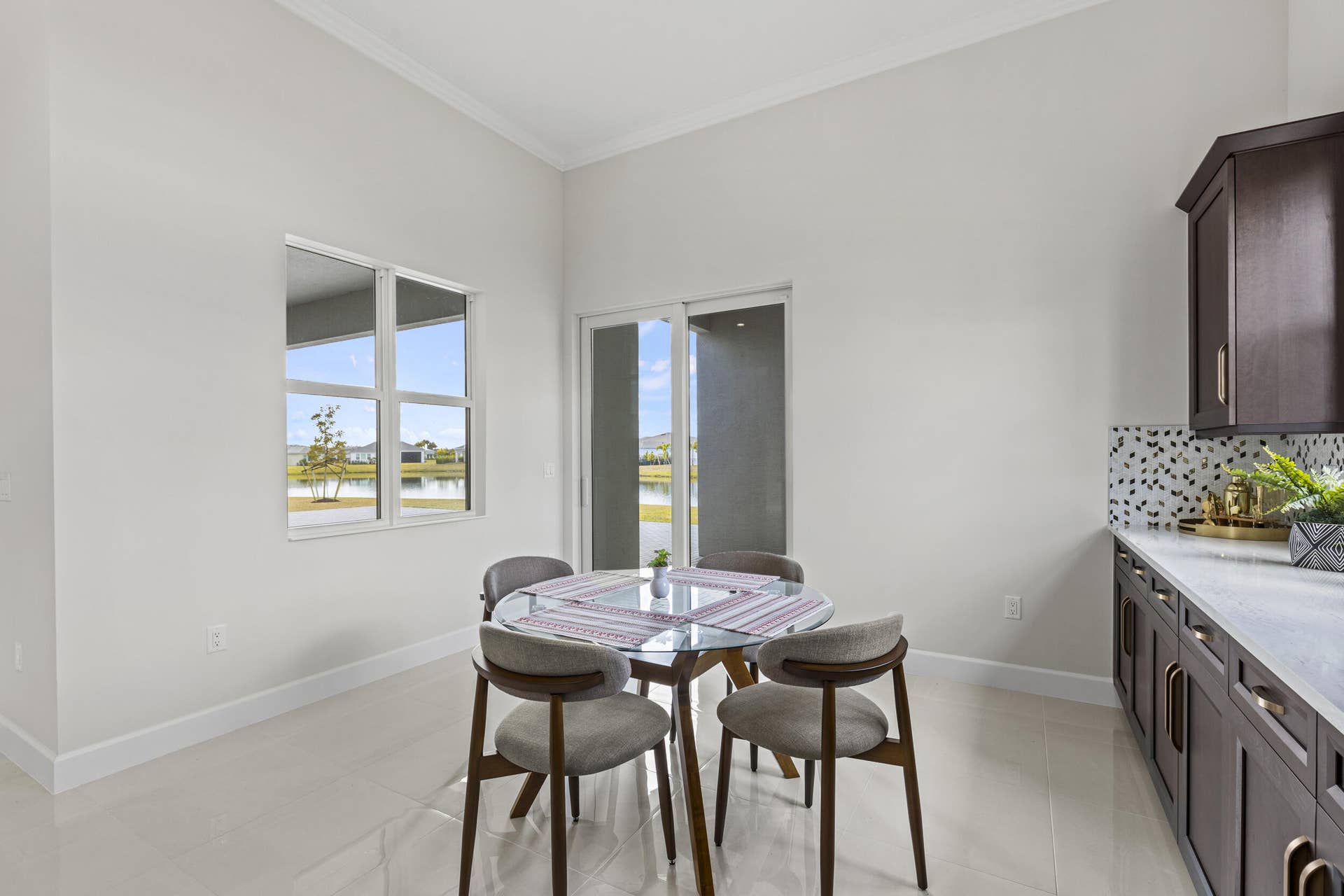14976 Woodlot Court, Westlake, FL 33470 Light-toned tile flooring, contemporary cabinetry with gold-toned hardware, patterned tile backsplash, and a sliding glass door