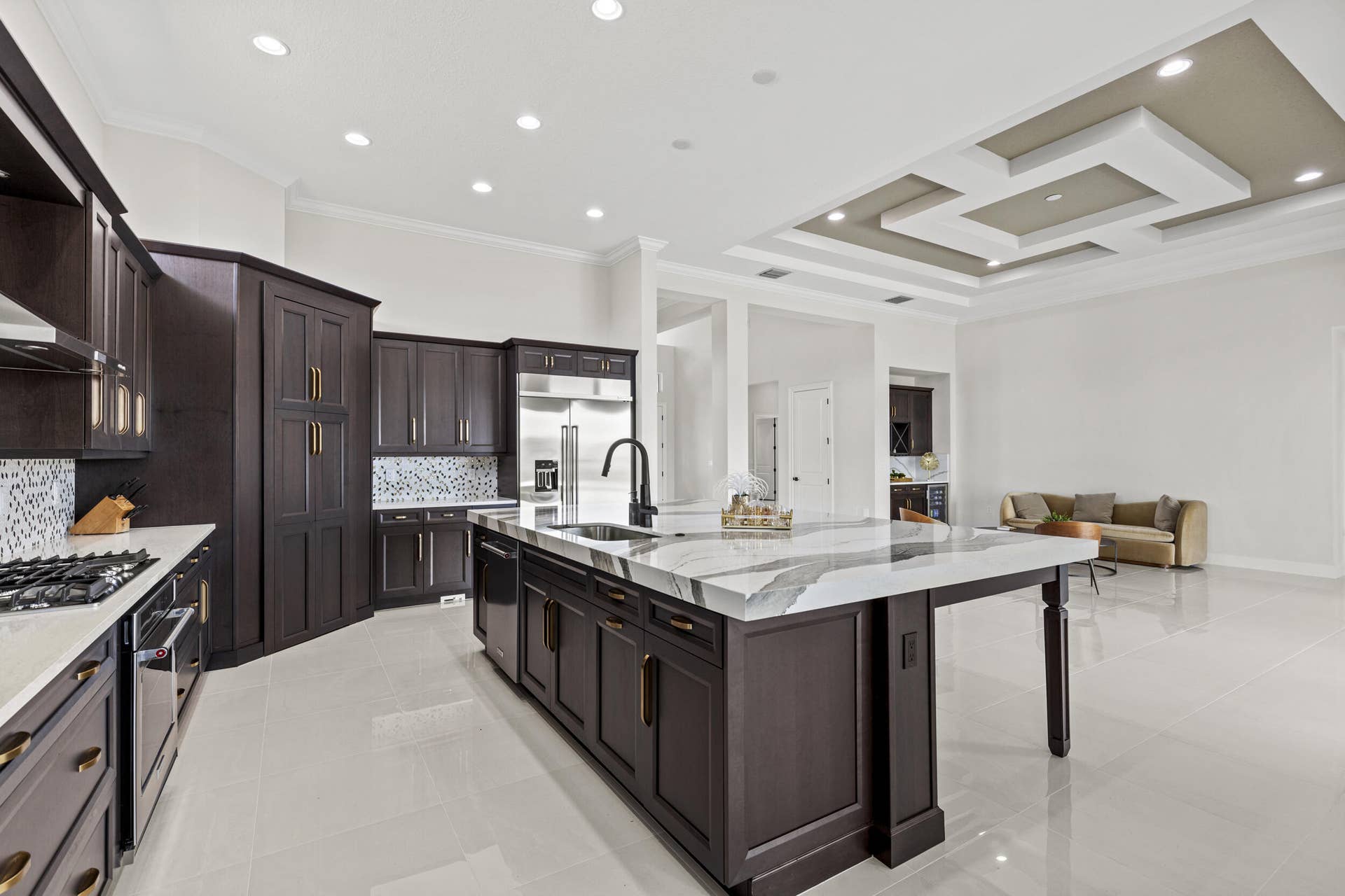 14976 Woodlot Court, Westlake, FL 33470 Kitchen featuring dark wood cabinetry, a large center island with a stone countertop, a stainless steel refrigerator, and a gas range
