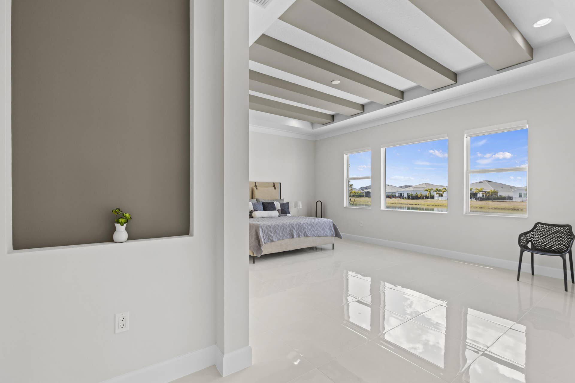 14976 Woodlot Court, Westlake, FL 33470 Owner's Suite featuring tray ceiling with decorative beams, large windows, recessed lighting, and tile flooring