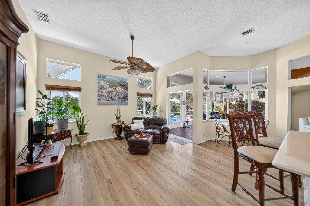 Vaulted ceilings featuring a ceiling fan, wood-finish flooring, and multiple windows