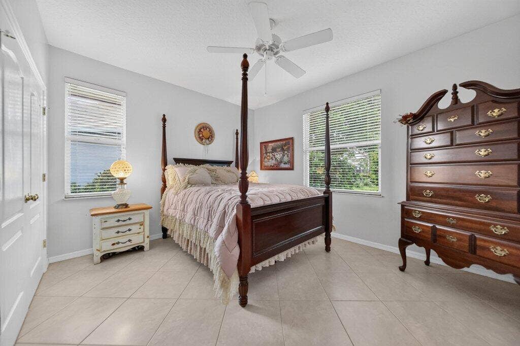 Guest room - Light-toned tile flooring, white ceiling fan, and two windows with blinds