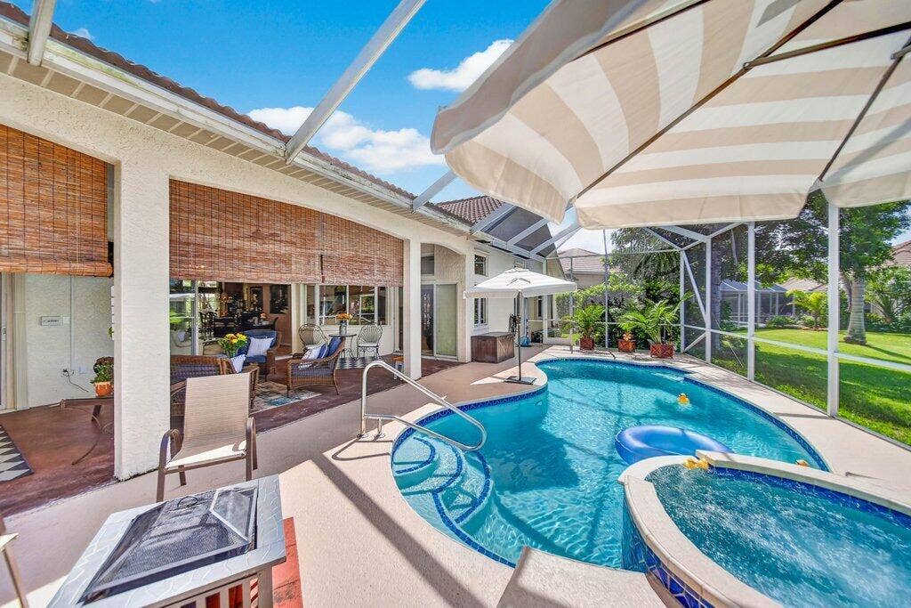 Screened-in patio featuring a tiled pool, integrated spa, and an expansive concrete pool deck