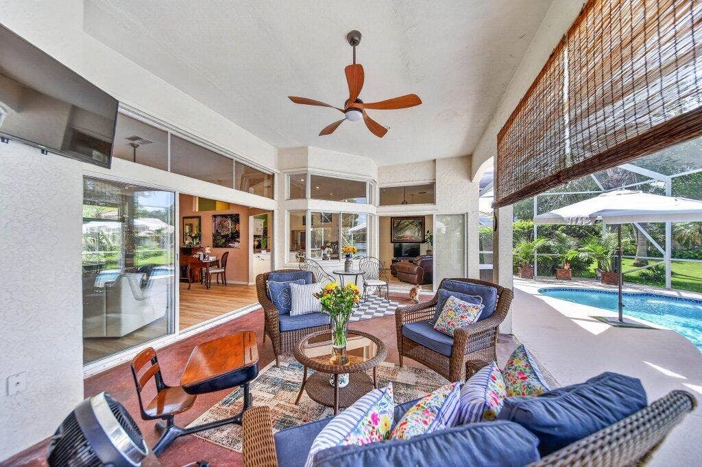 Covered patio with ceiling fan, sliding glass doors, transom windows, and an outdoor pool
